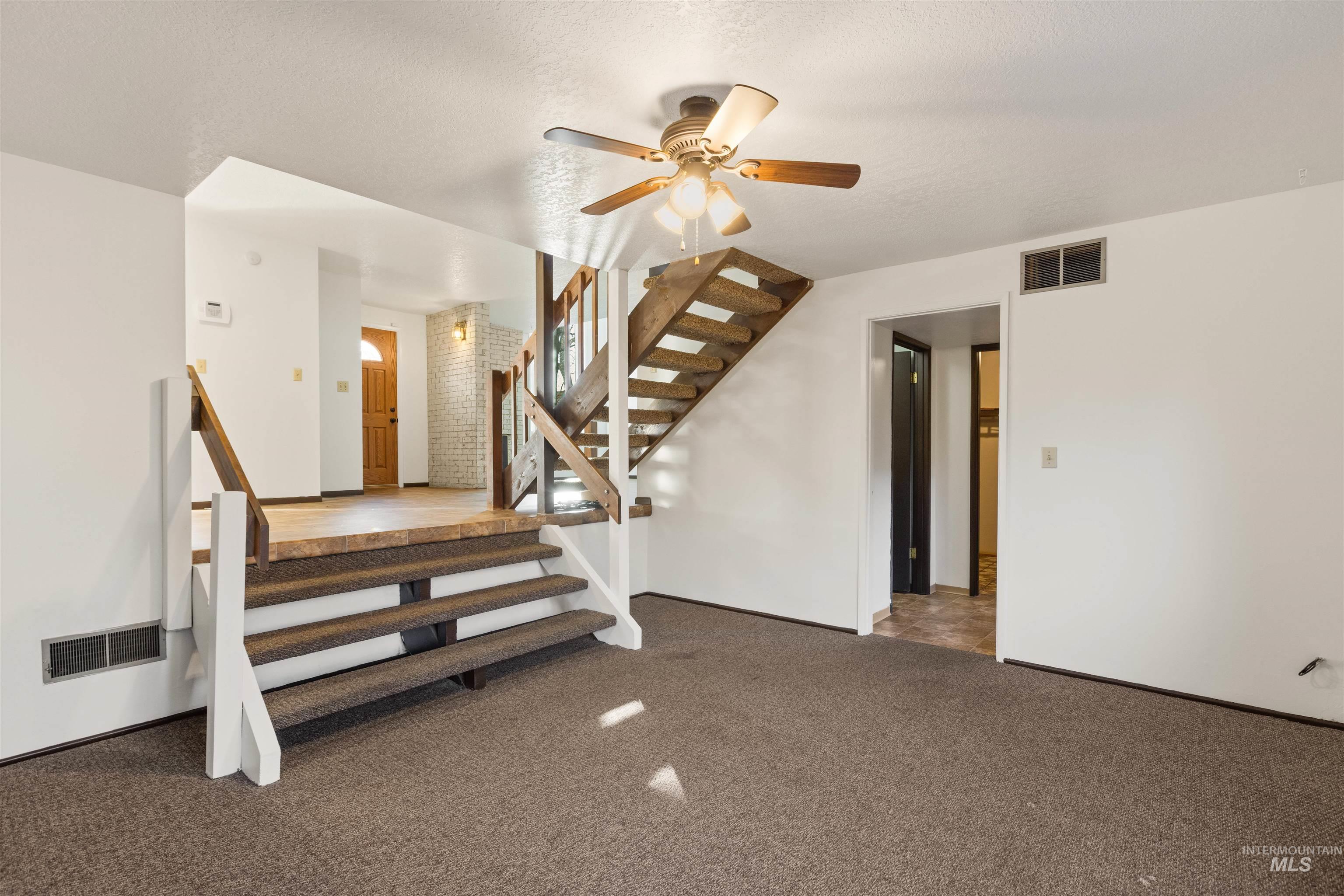Stairway with carpet flooring, ceiling fan, and a textured ceiling