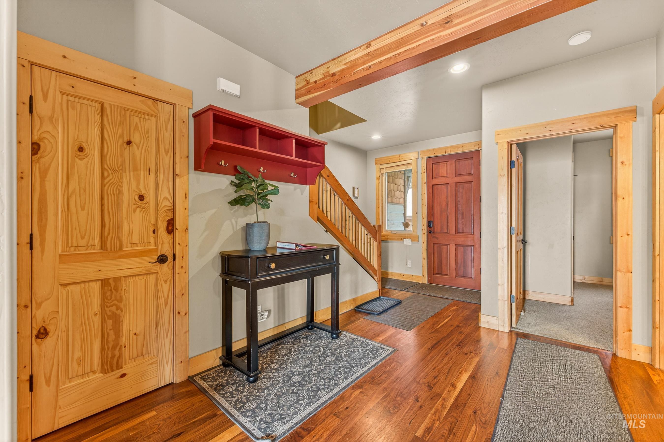 Foyer entrance with beamed ceiling, wood finished floors, stairway, and recessed lighting