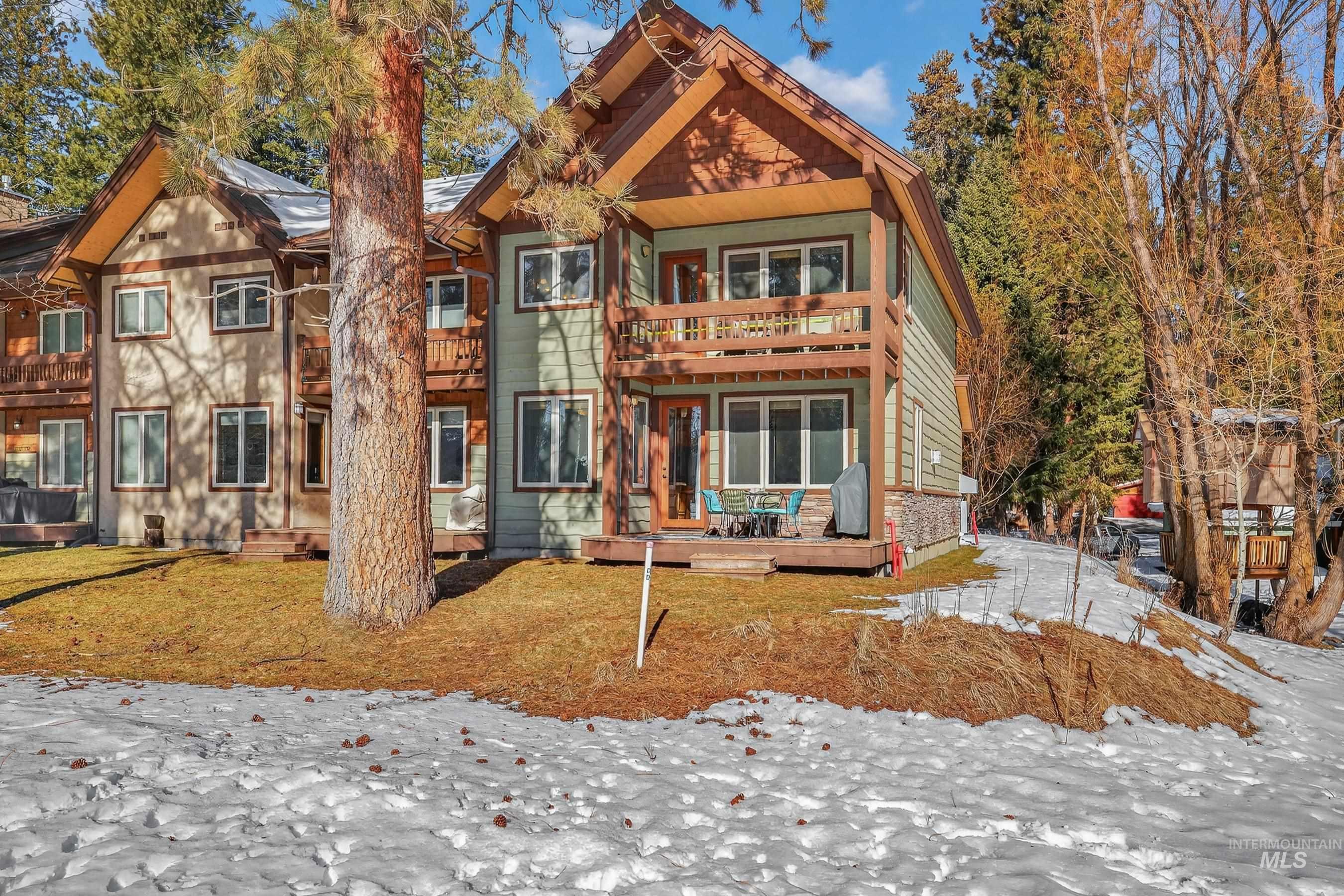 Snow covered rear of property featuring a balcony and a wooden deck