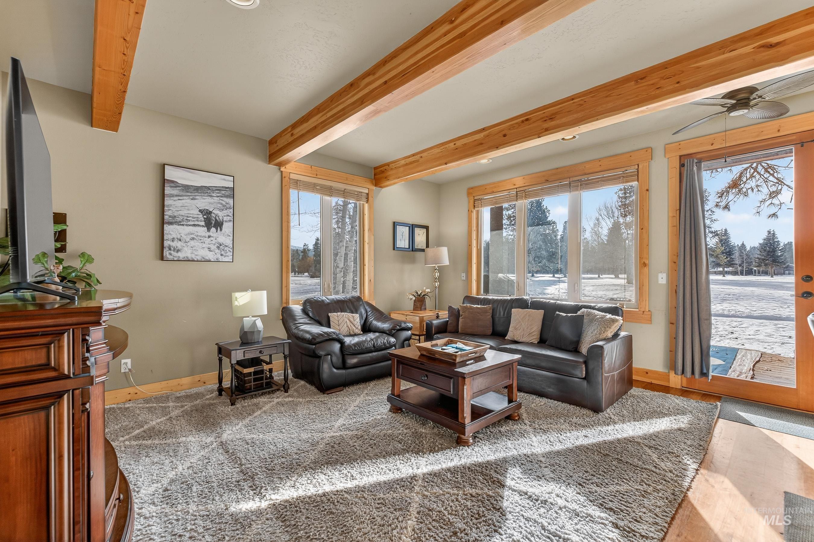 Living area featuring ceiling fan and beam ceiling