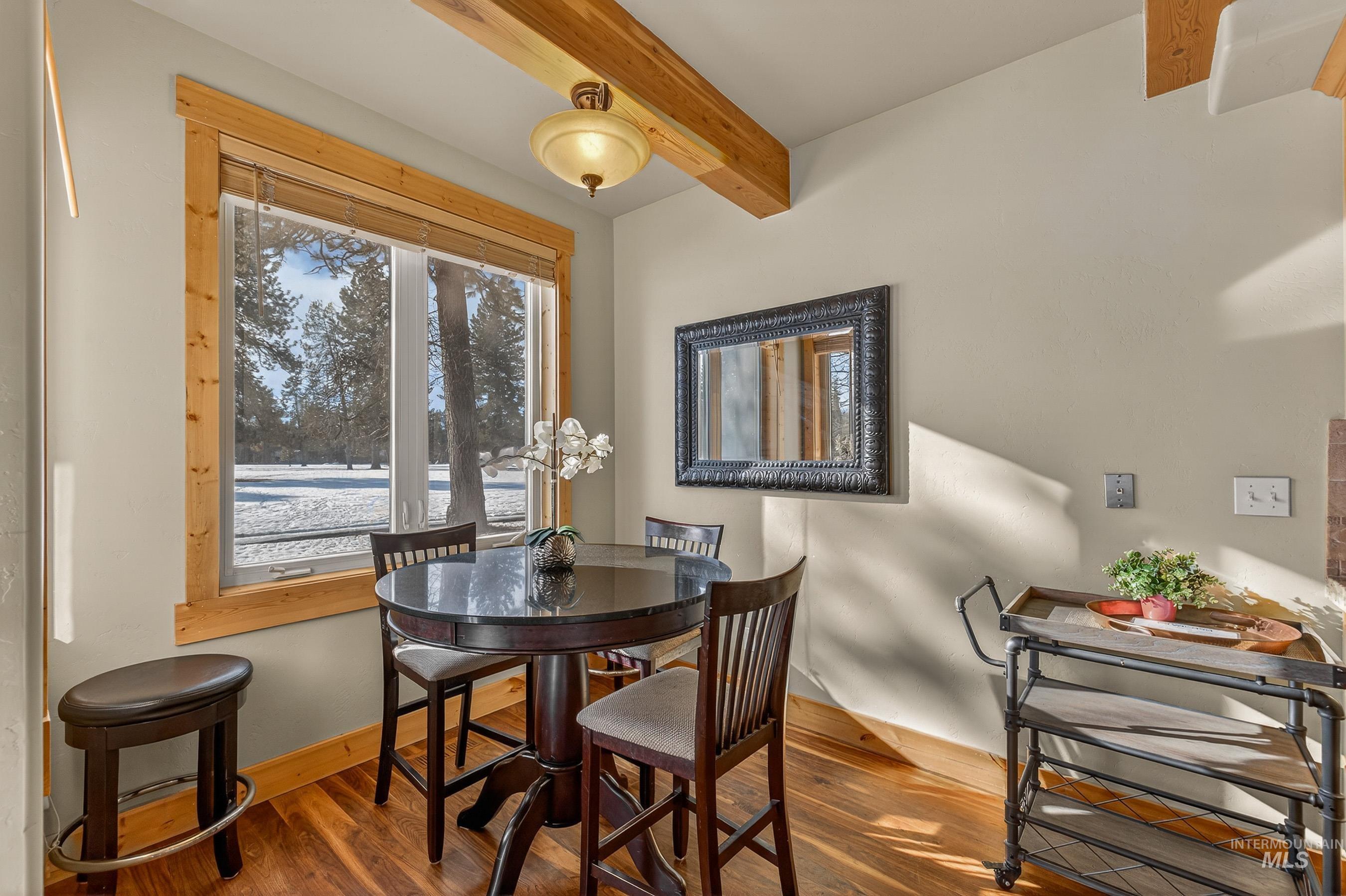 Dining area featuring wood finished floors and beamed ceiling
