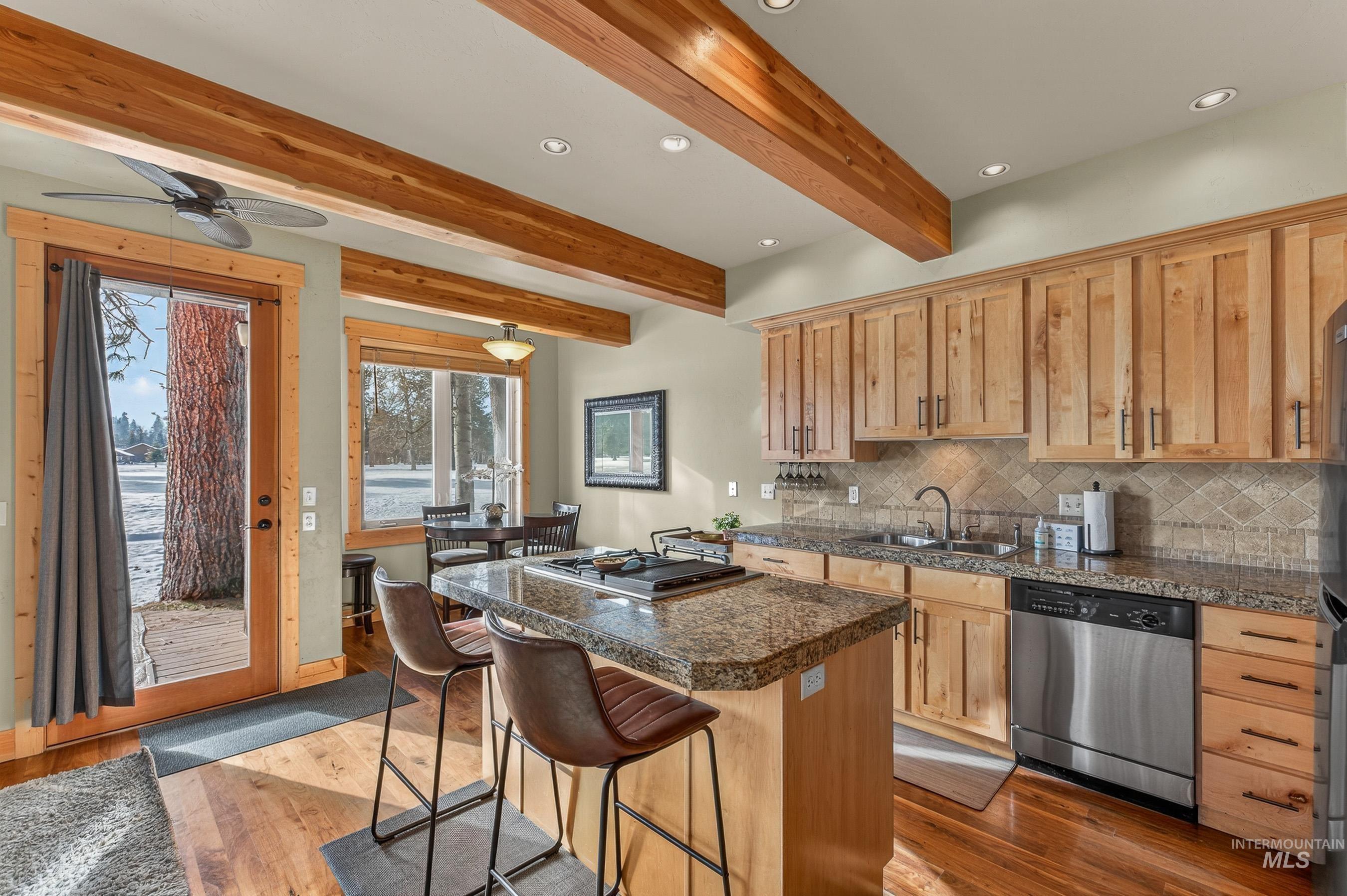 Kitchen with tile countertops, a center island, stainless steel appliances, a breakfast bar, and dark wood-type flooring