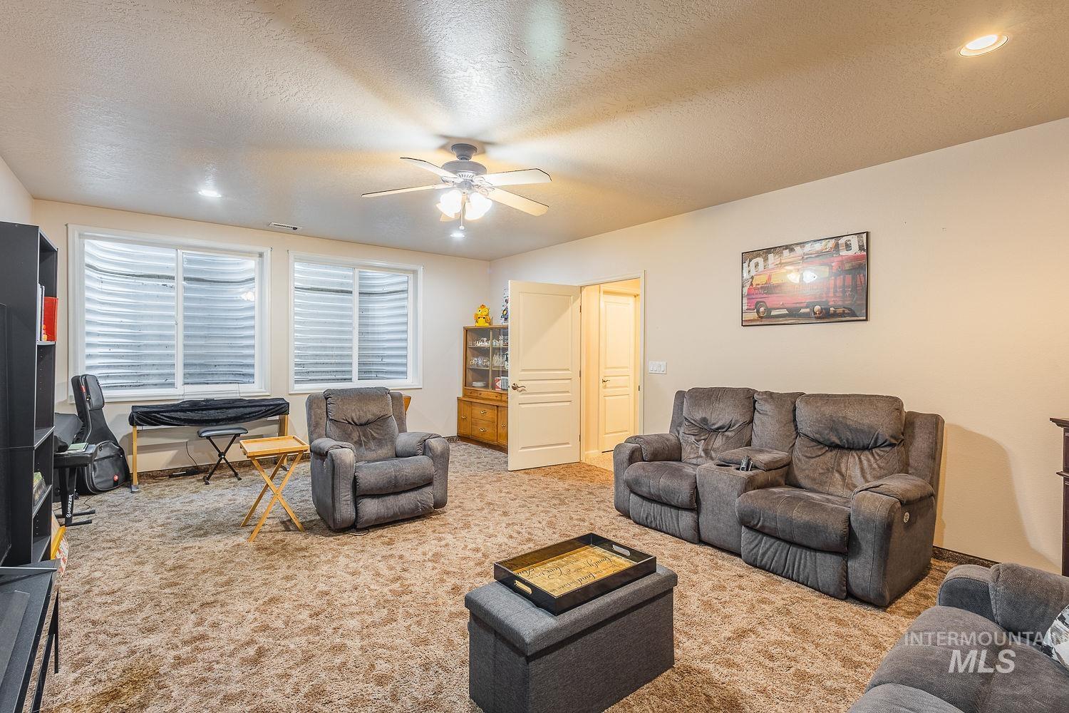 Living area with carpet floors, a textured ceiling, and a ceiling fan