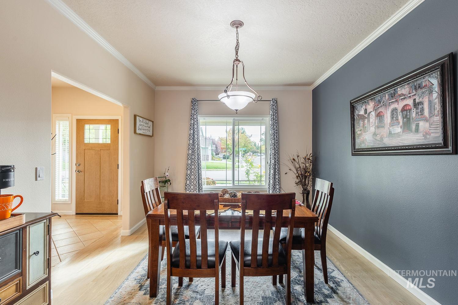 Dining space with light wood-style floors, ornamental molding, and a textured ceiling