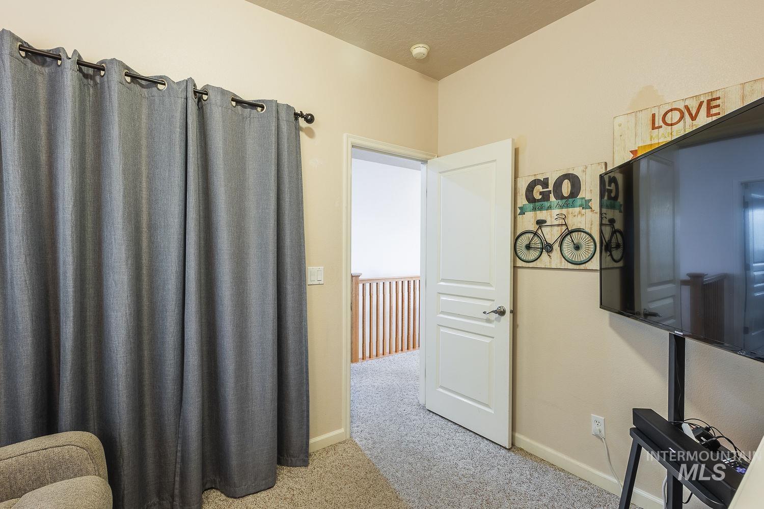 Hallway with light carpet and a textured ceiling