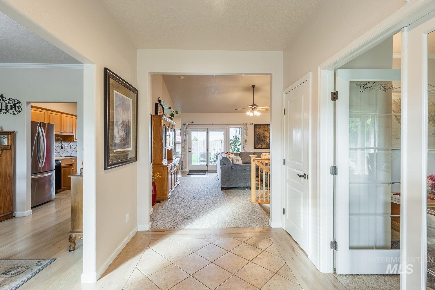Hall featuring light tile patterned floors, a textured ceiling, and light colored carpet