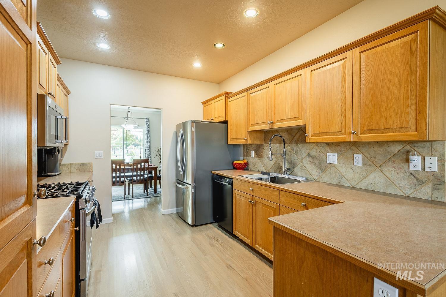 Kitchen featuring stainless steel appliances, backsplash, light countertops, recessed lighting, and hanging light fixtures