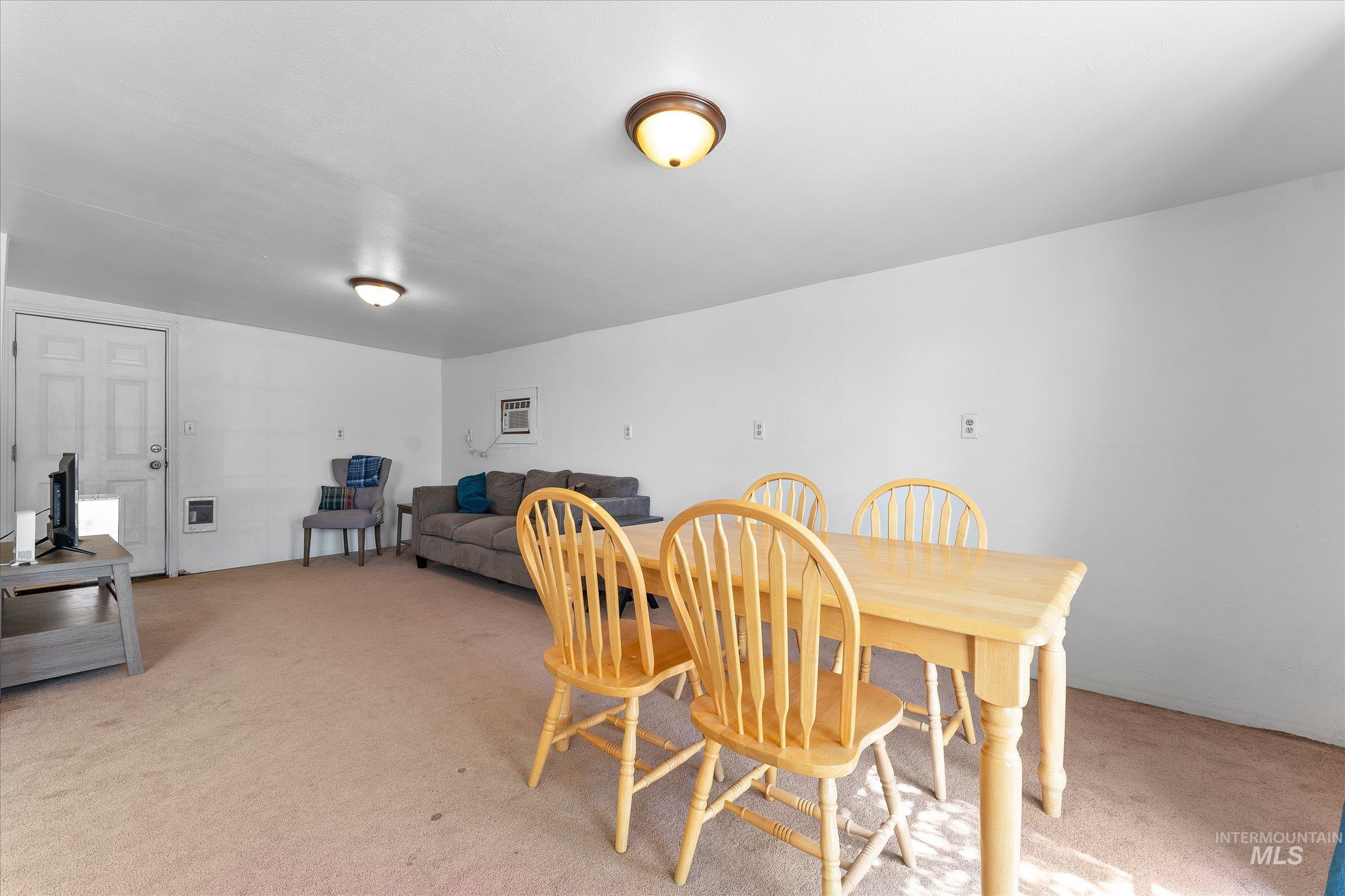 Dining space with light colored carpet and a wall unit AC