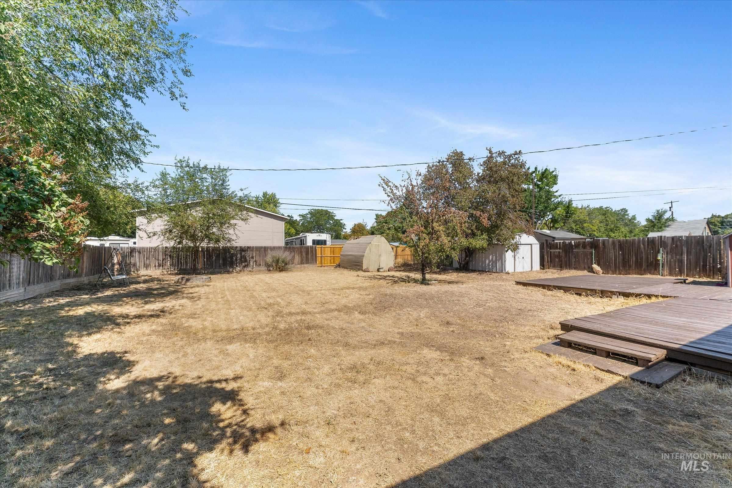 Fenced backyard with a deck and a storage unit