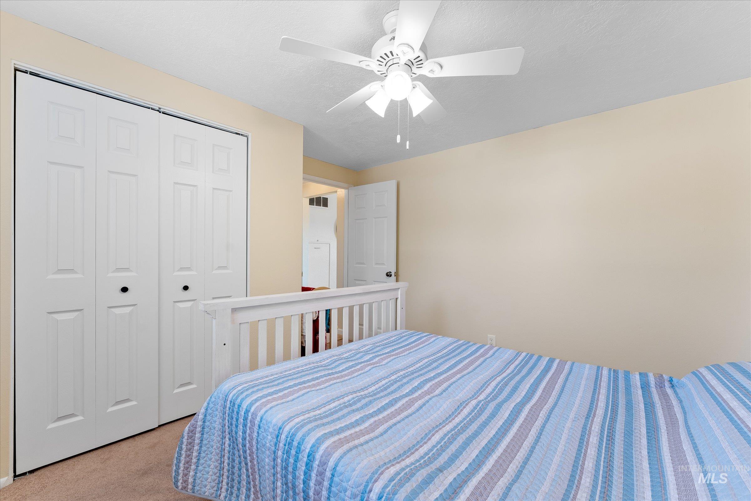 Carpeted bedroom featuring ceiling fan and a closet