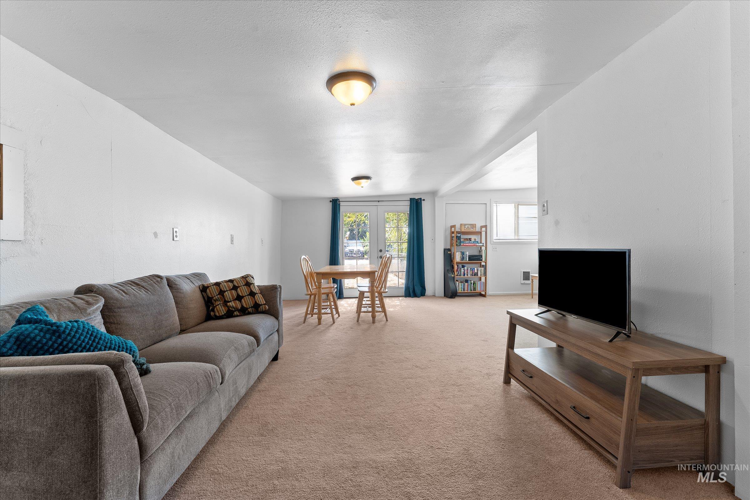 Living area featuring light colored carpet, french doors, and a textured ceiling