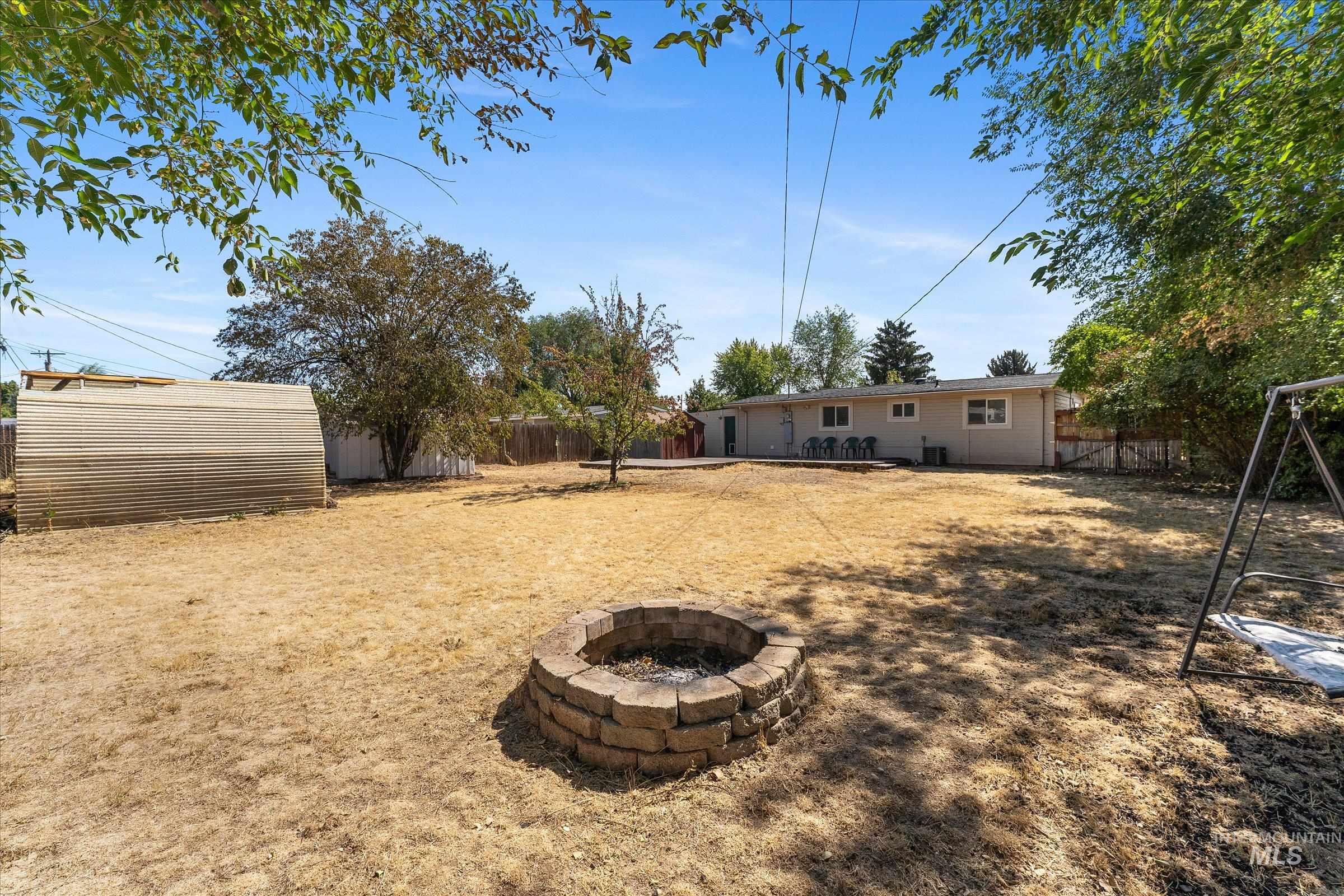 Fenced backyard featuring a patio area and a fire pit