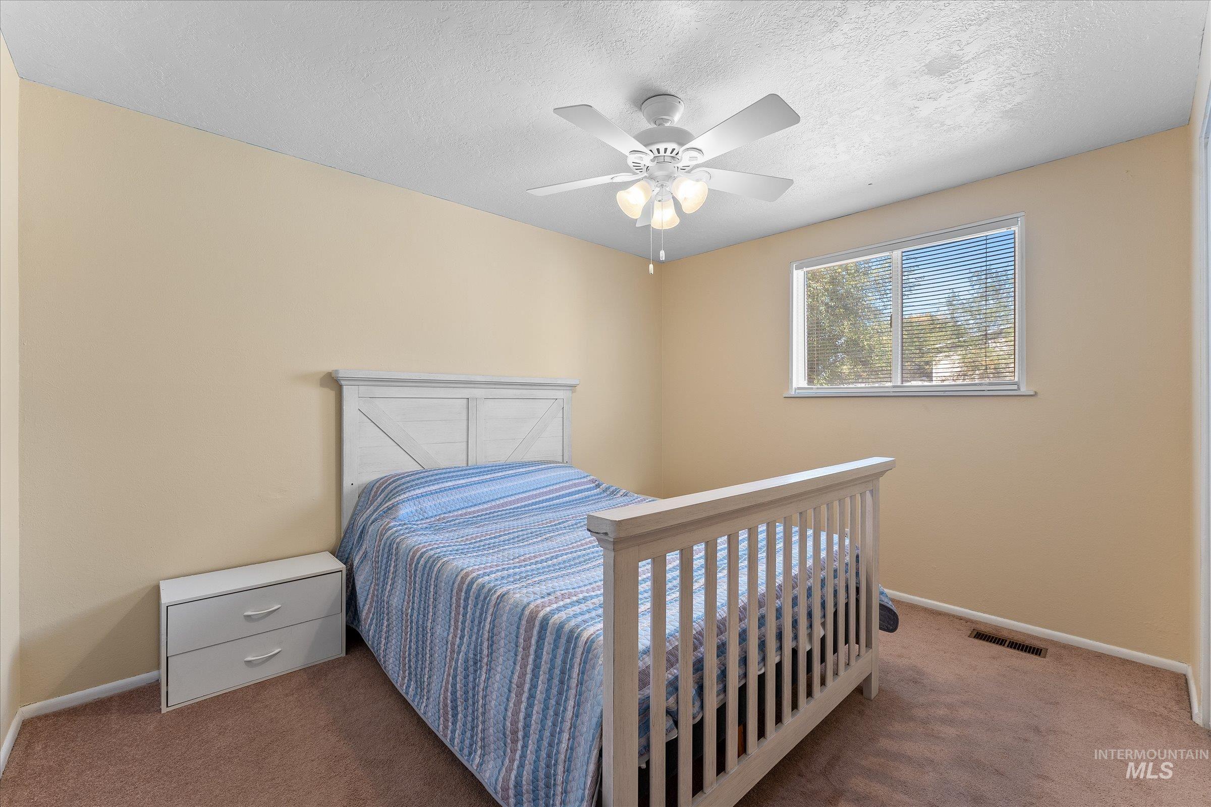Carpeted bedroom with a textured ceiling and a ceiling fan
