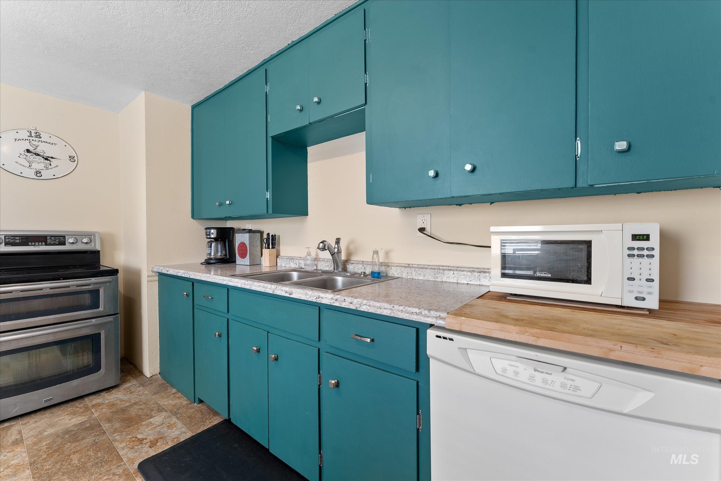 Kitchen featuring white appliances, light countertops, blue cabinets, and a textured ceiling