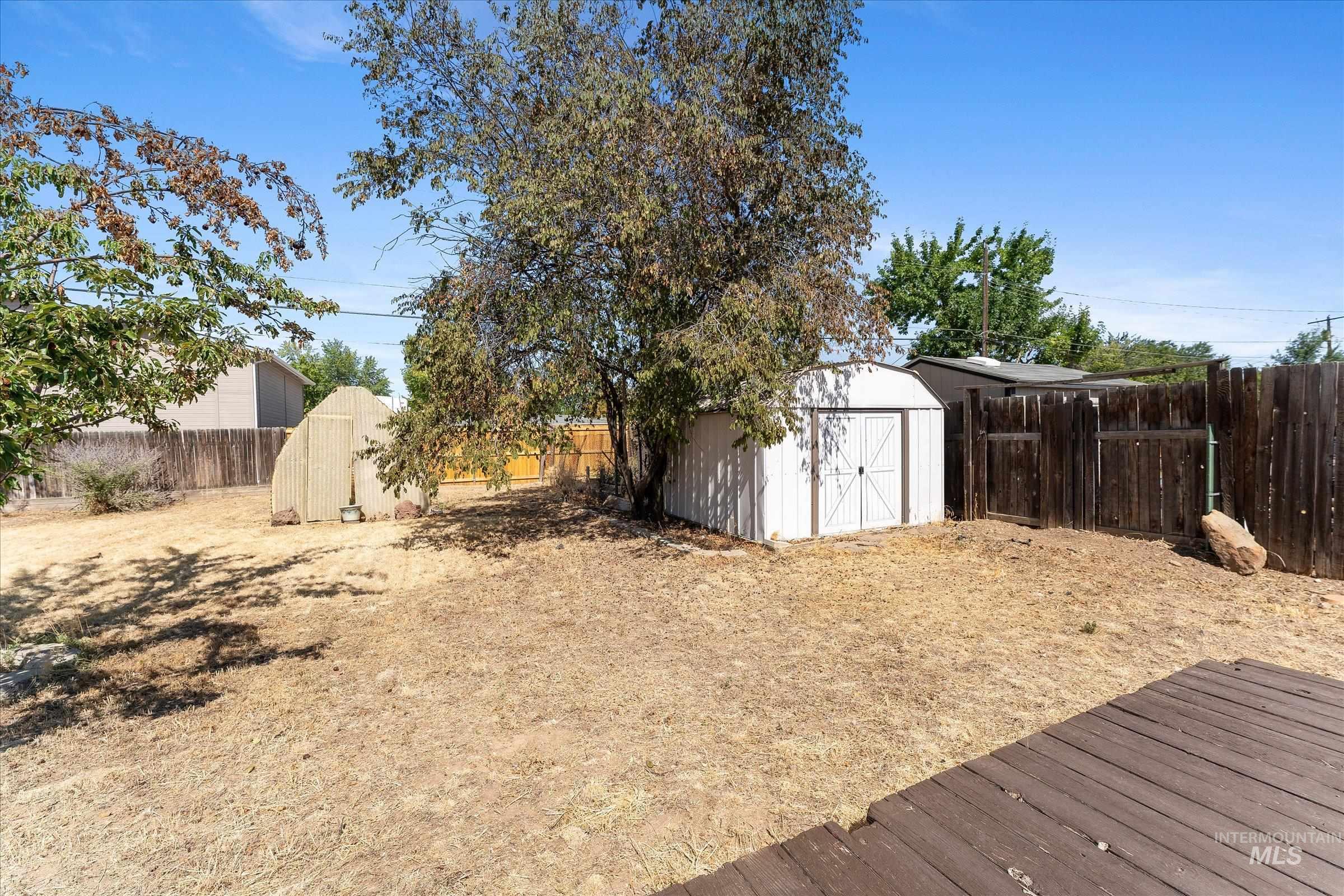 Fenced backyard featuring a storage shed