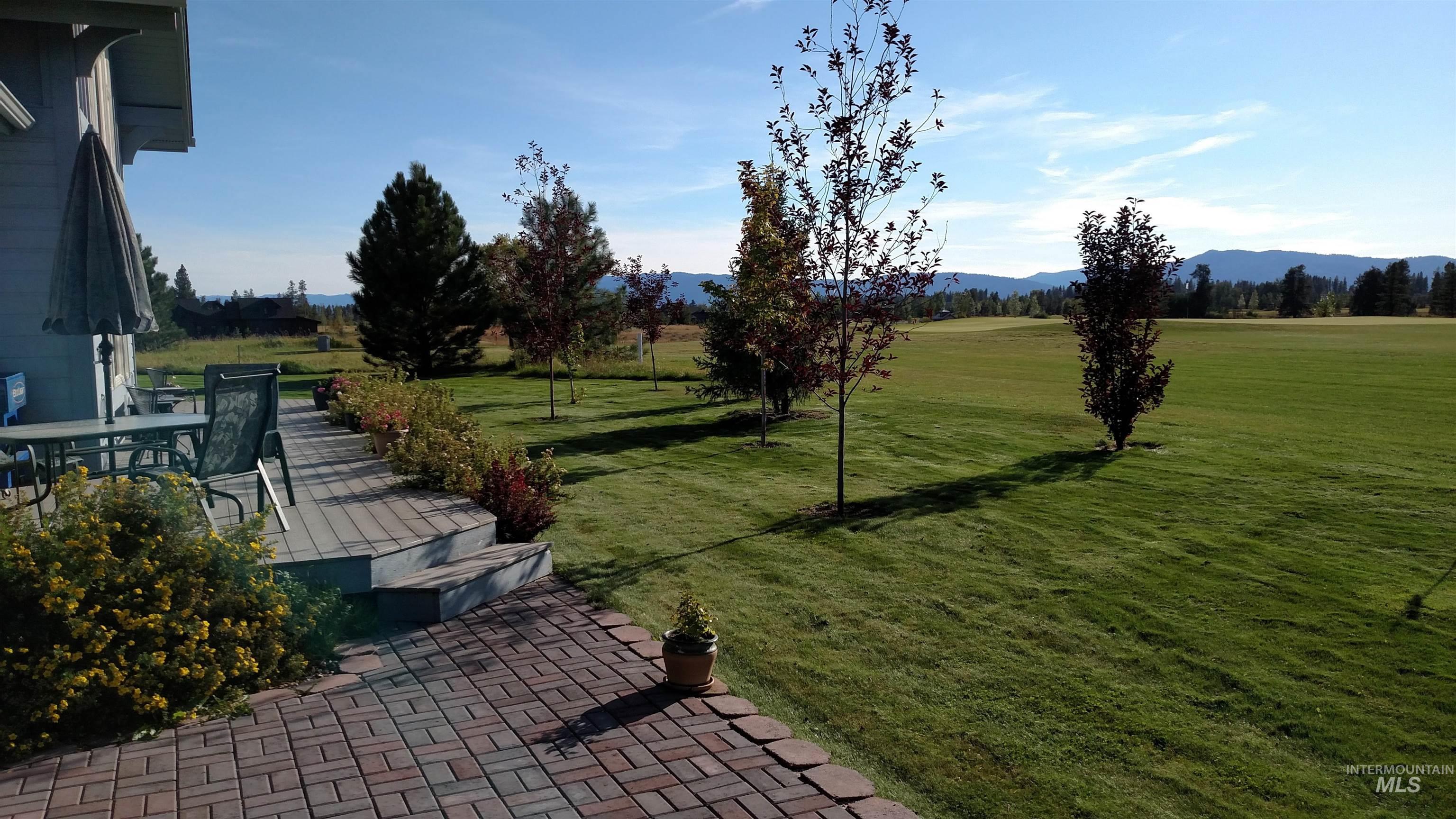 View of green lawn featuring a patio, a mountain view, and outdoor dining area