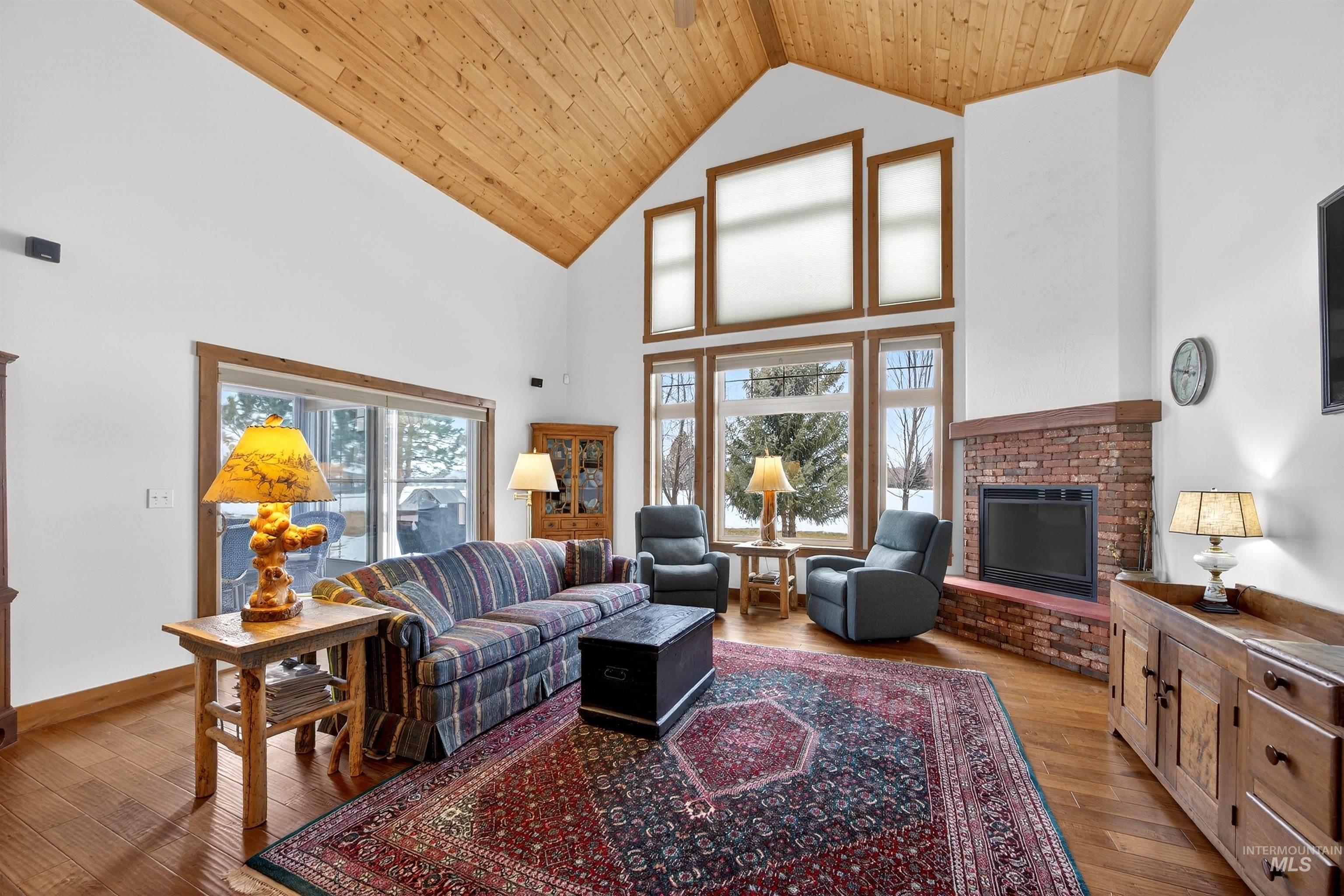 Living room with a fireplace, a high wood ceiling, and light wood-type flooring