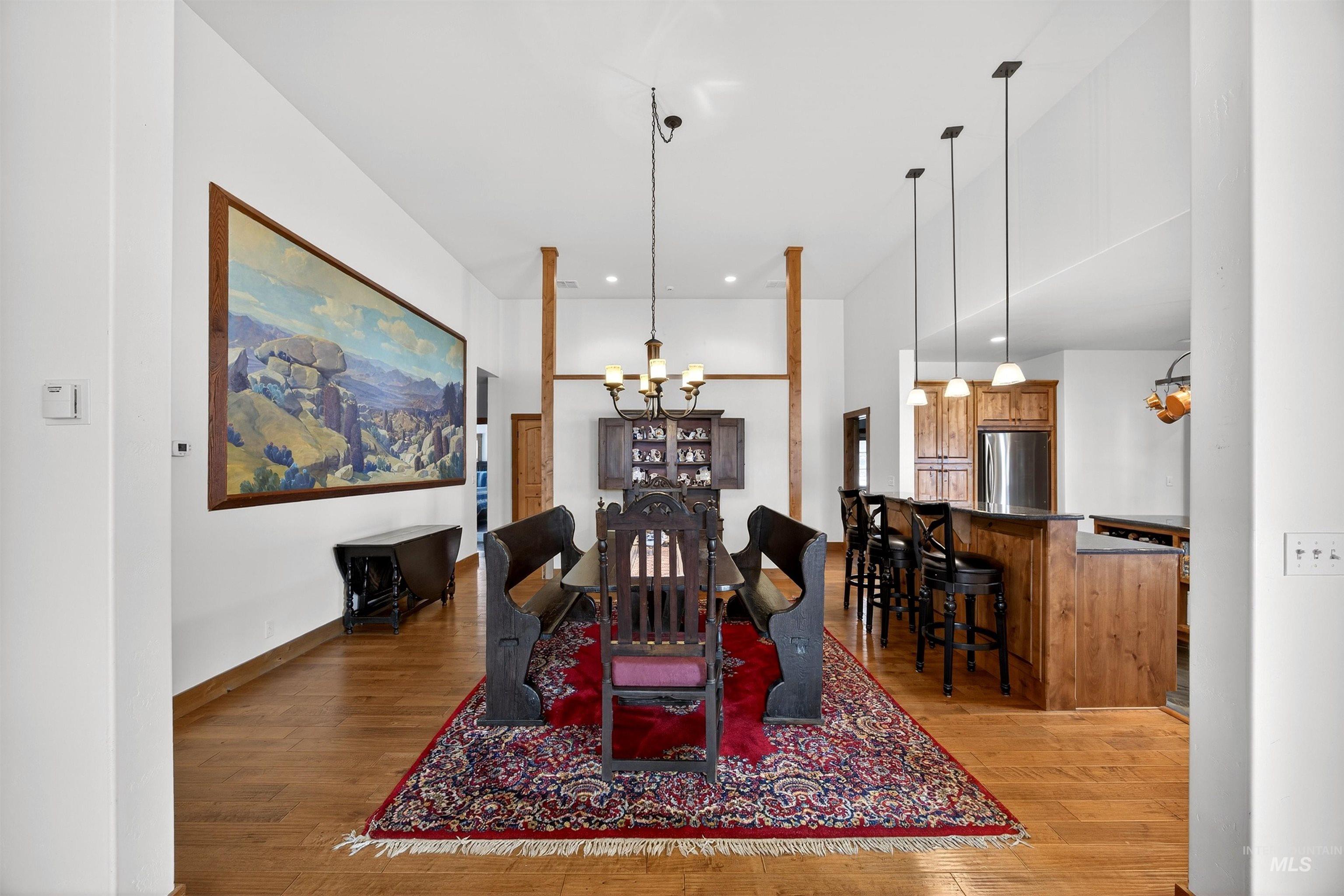Dining space featuring light wood-style flooring, hanging lights, and a high ceiling