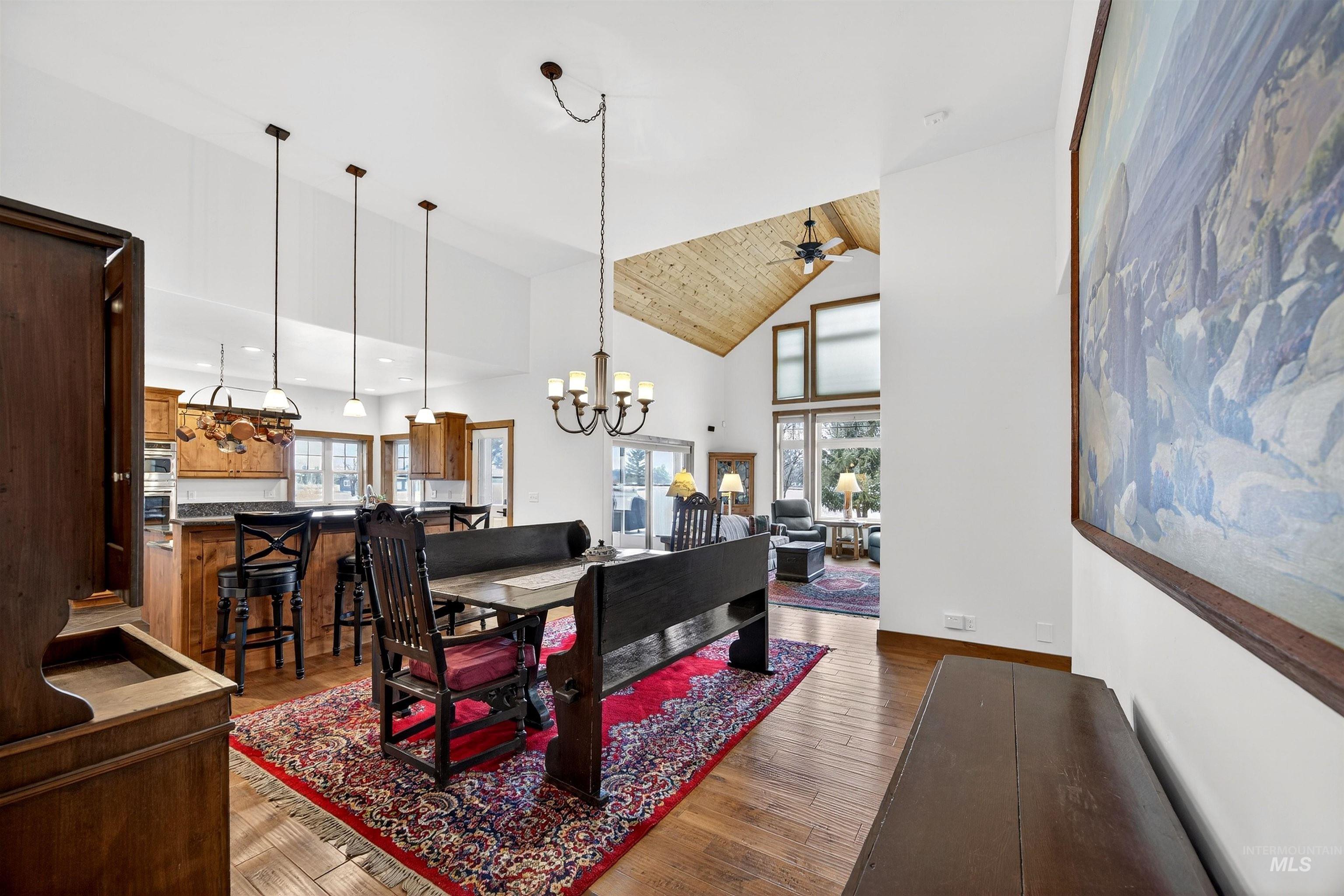 Dining space with suspended lighting, wood-type flooring, lofted ceiling, plenty of natural light, and ceiling fan
