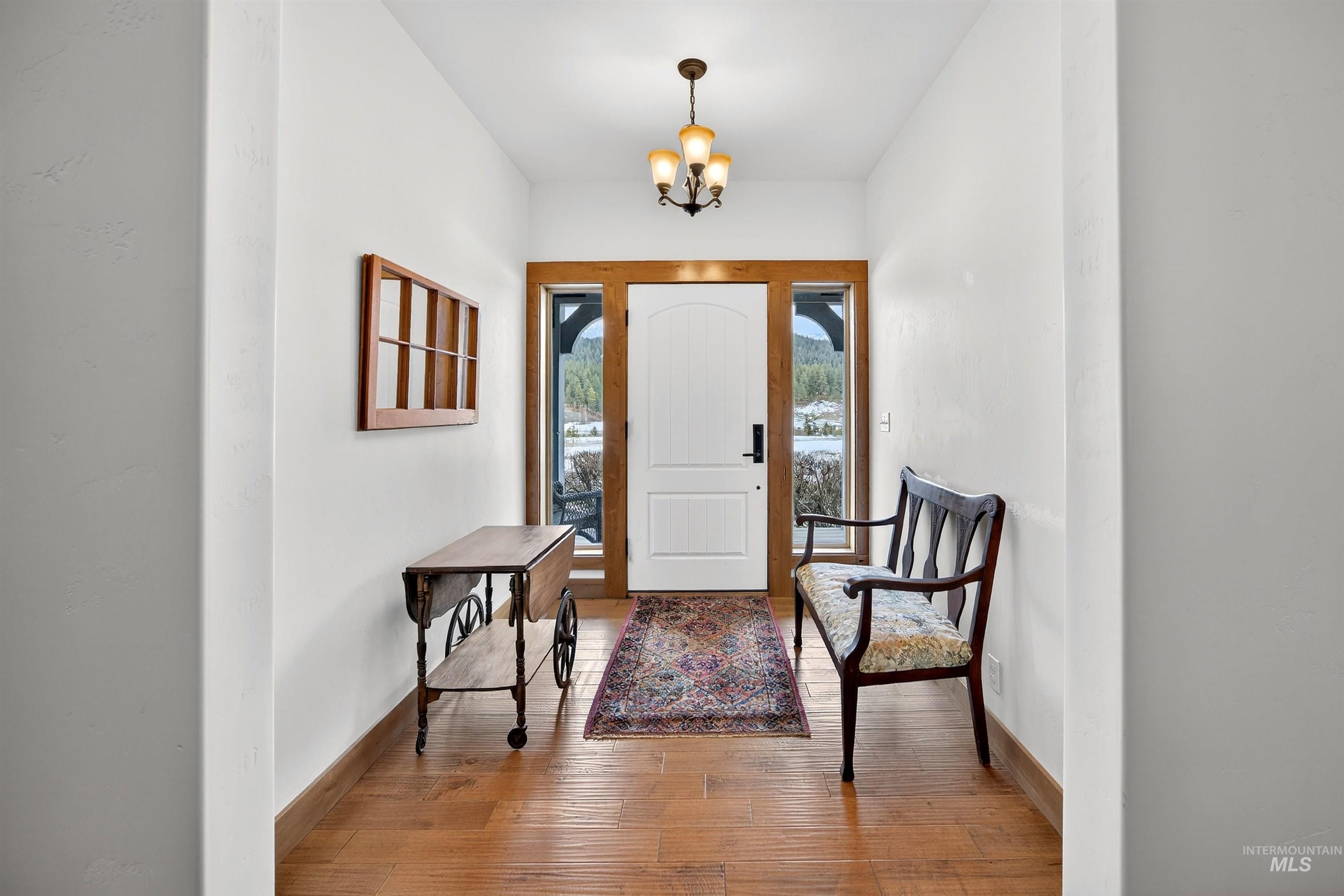 Entryway featuring a white paneled door with sidelights, wood-finish flooring, a decorative area rug, and a ceiling-mounted fixture