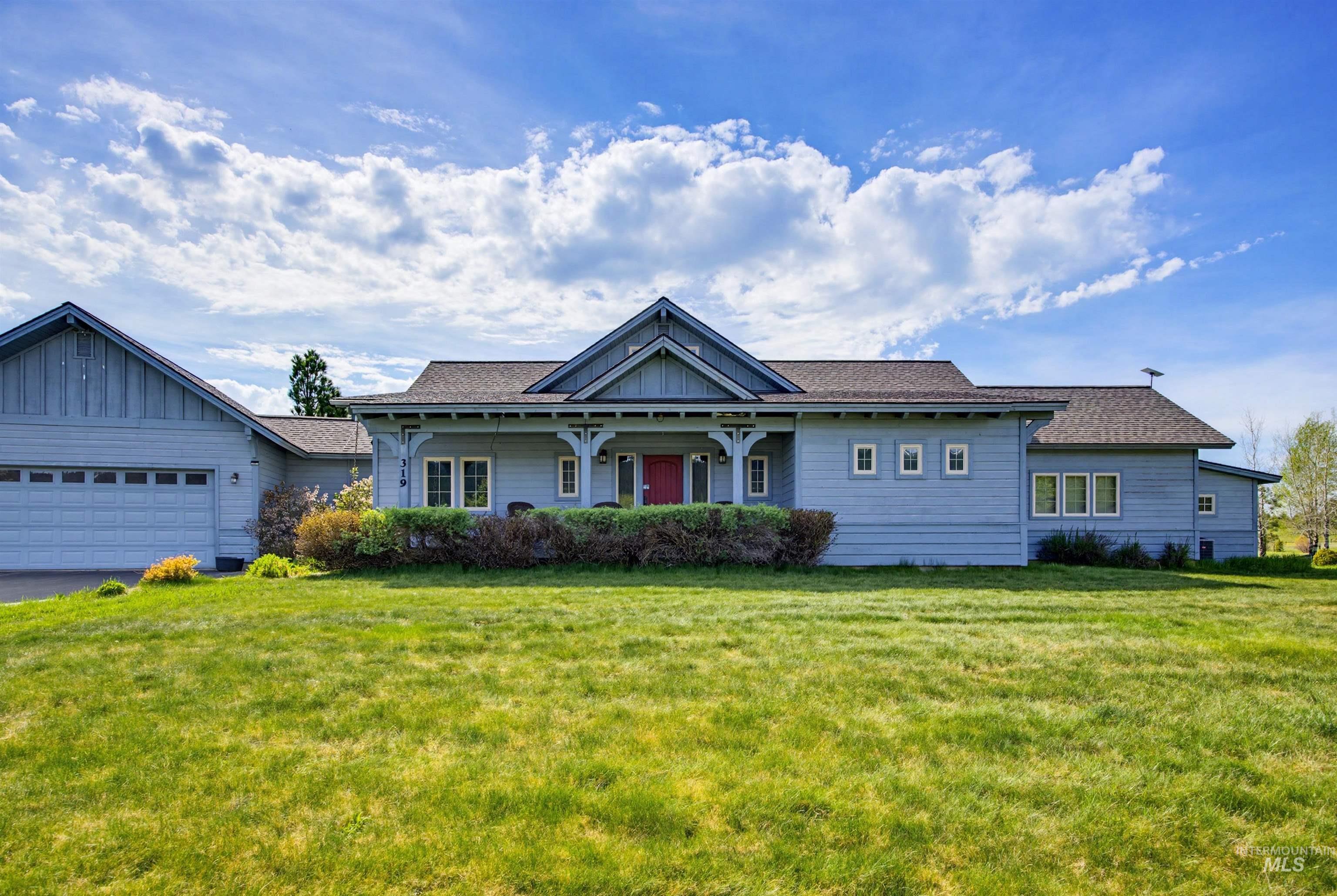 Craftsman-style exterior with light blue siding, a covered porch with white columns, and a prominent red entry door