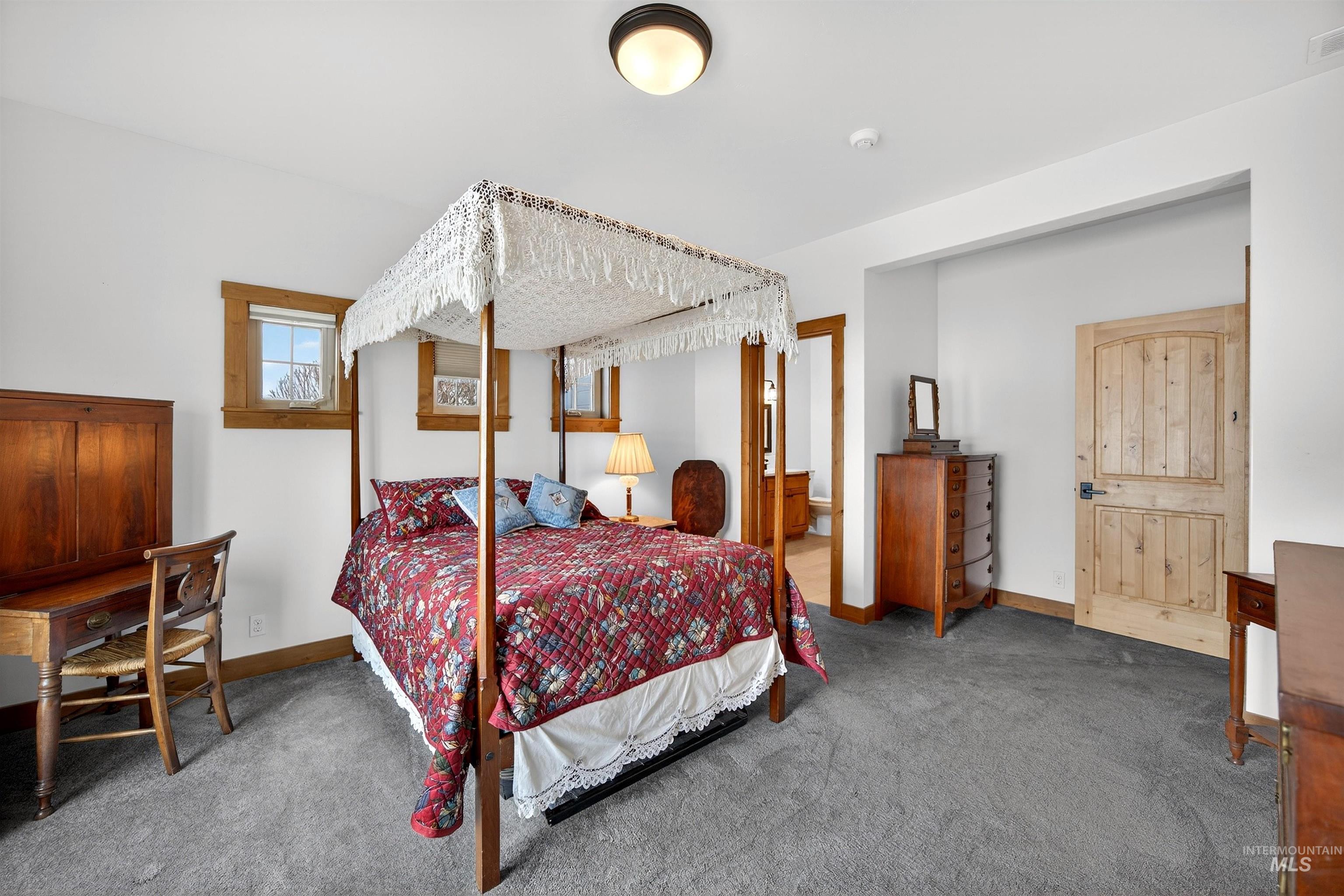 Bedroom featuring light gray carpeting, crisp white walls, and natural wood window trim