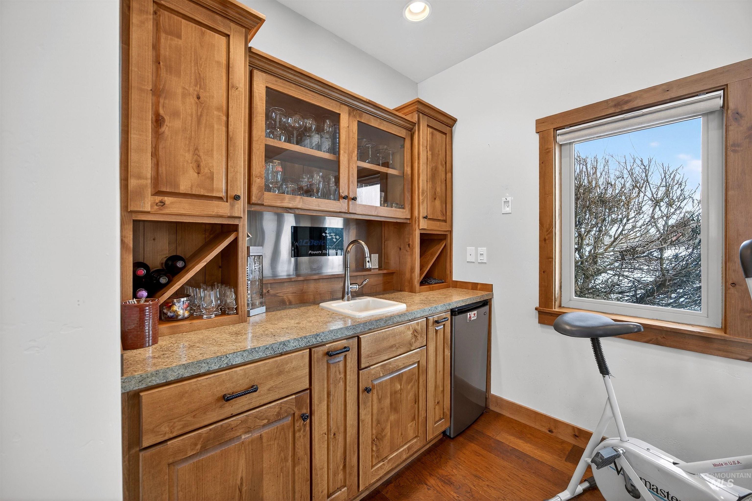 Bar with glass fronted cabinets, wood finish cabinets, dark wood finished floors, dishwasher, and recessed lighting