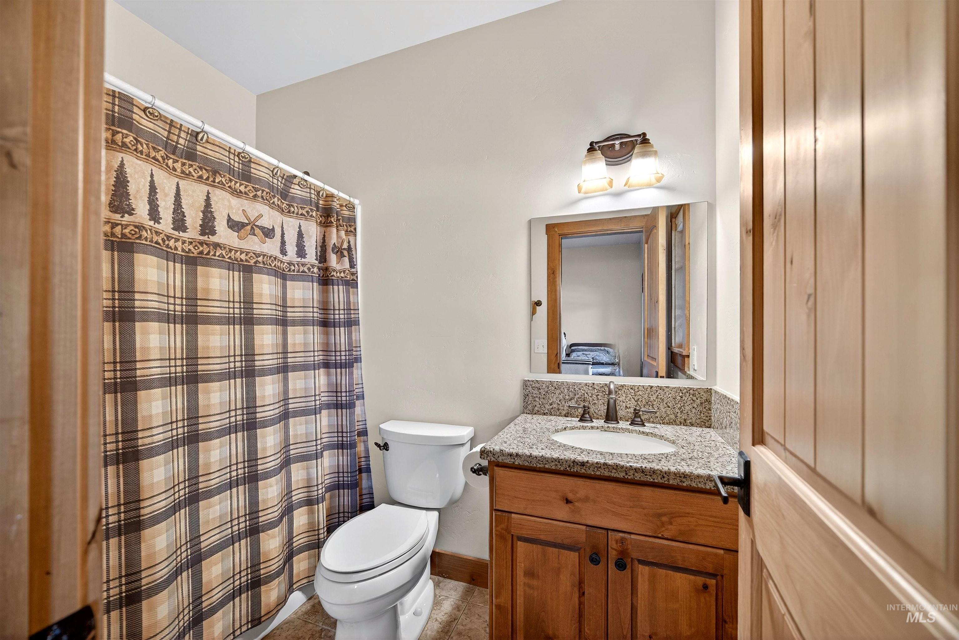 Bathroom featuring a wooden vanity with a granite countertop, undermount sink, and a framed mirror