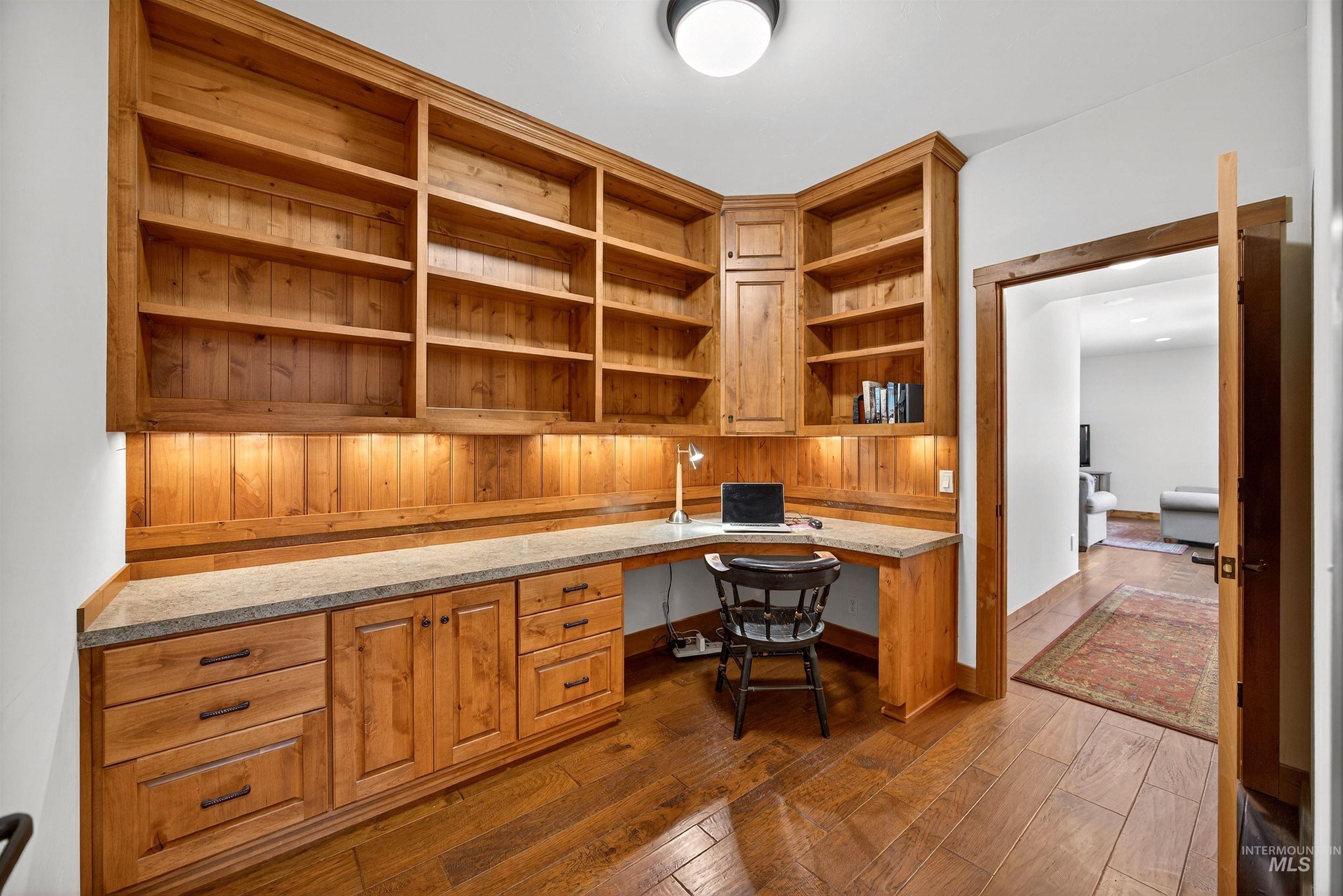 Built-in corner desk and shelving unit crafted from natural wood, featuring under-cabinet lighting
