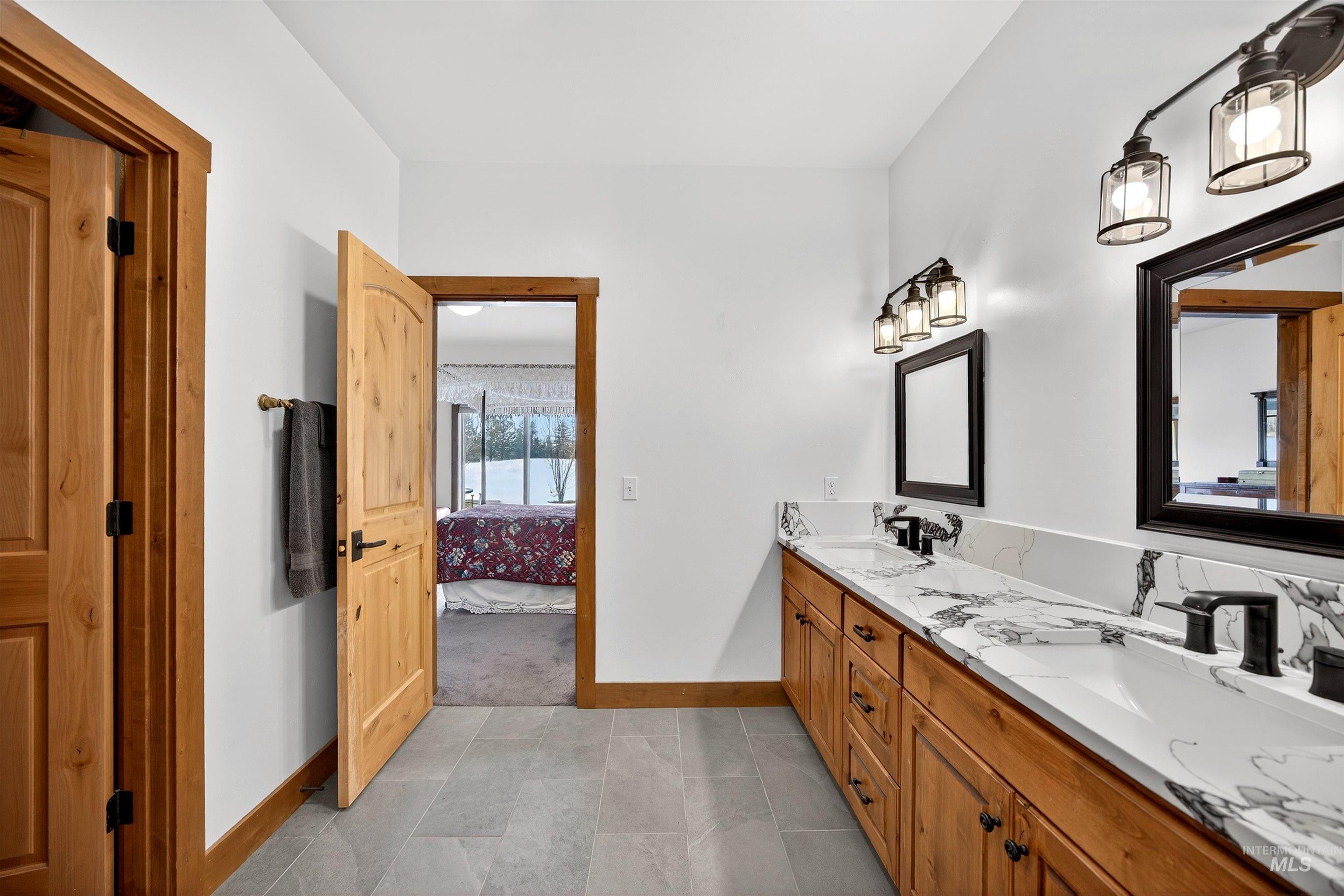 Dual vanity featuring integrated sinks, black fixtures, and a white countertop with grey veining