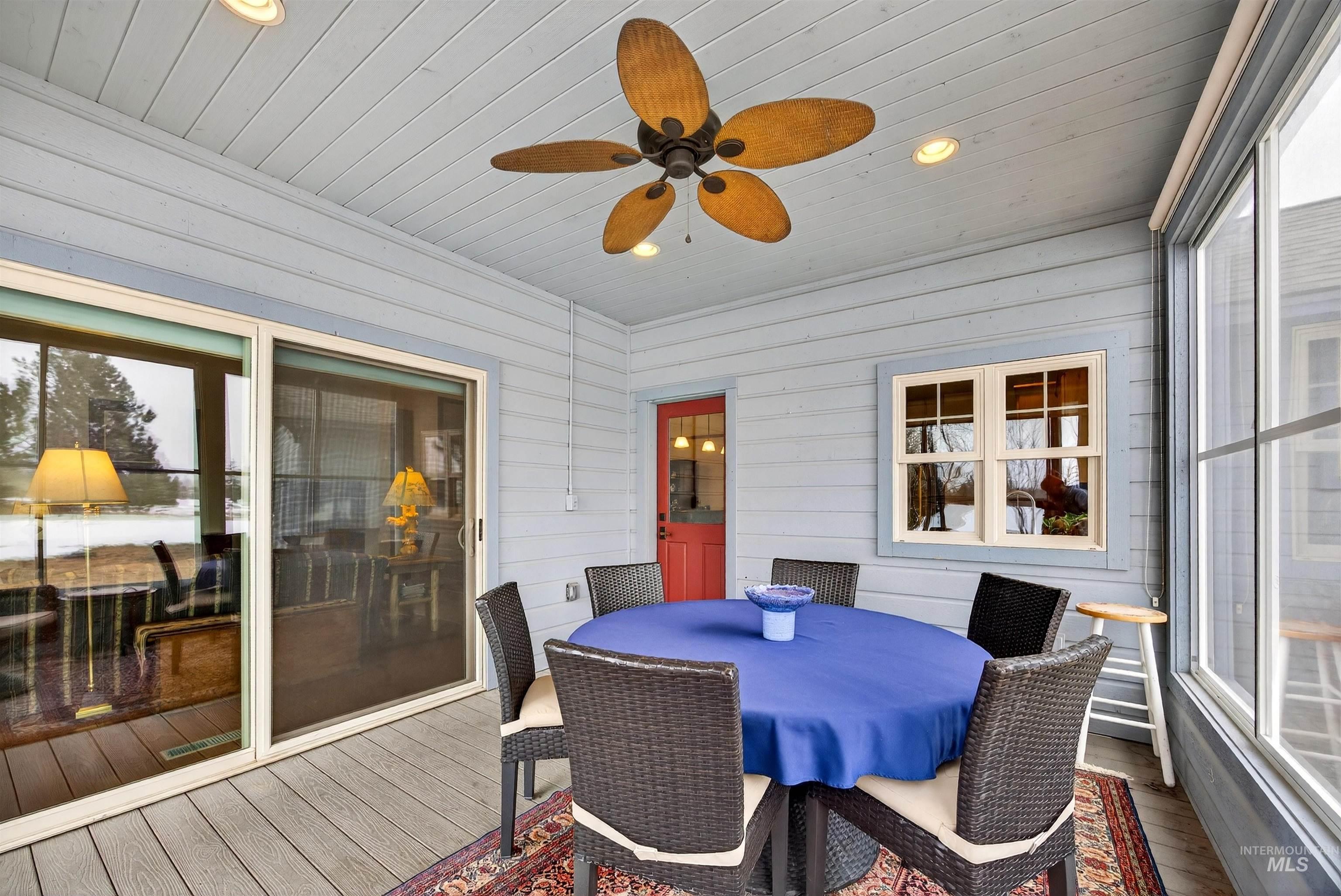 Screened porch featuring a natural wood-finish ceiling fan, recessed lighting, light blue horizontal siding, and large sliding glass doors