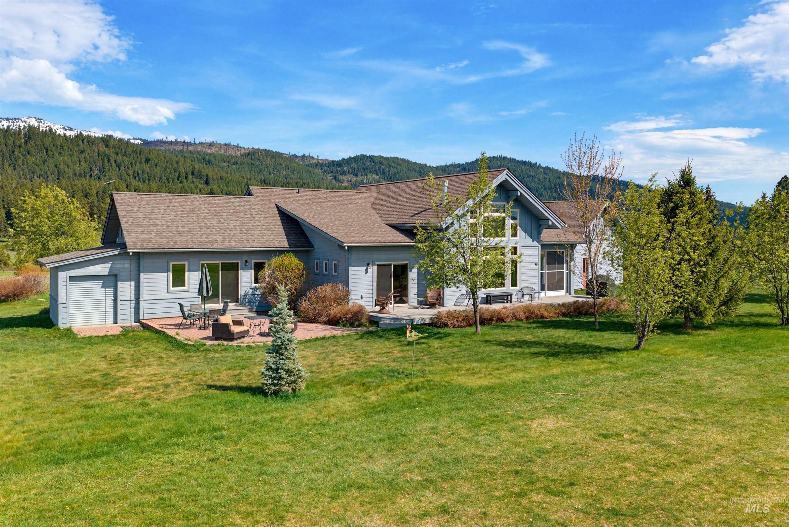 Spacious exterior featuring light blue siding, a multi-gabled roofline, and extensive picture windows