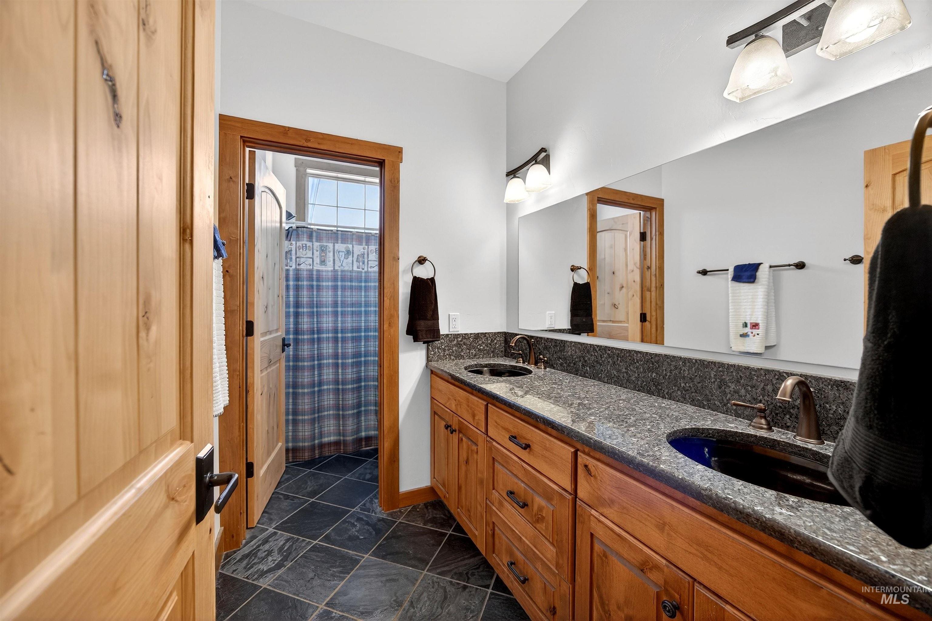 Bathroom featuring a double vanity with stone countertops, dark basin sinks, and bronze-finish fixtures