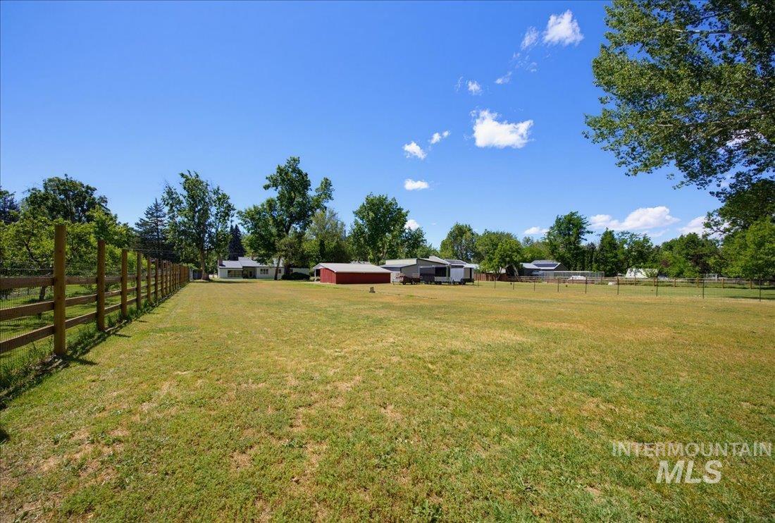 Expansive grassy area featuring a wooden fence and mature trees