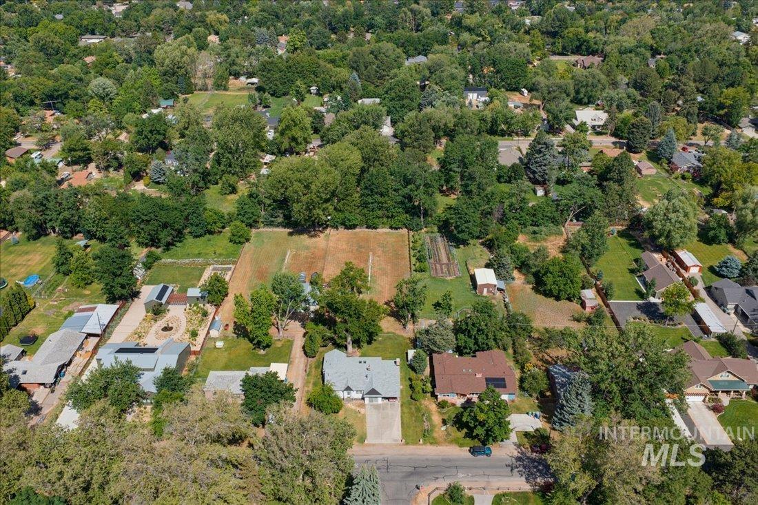 Expansive property featuring a large cultivated area, mature trees, multiple outbuildings, and a landscaped yard