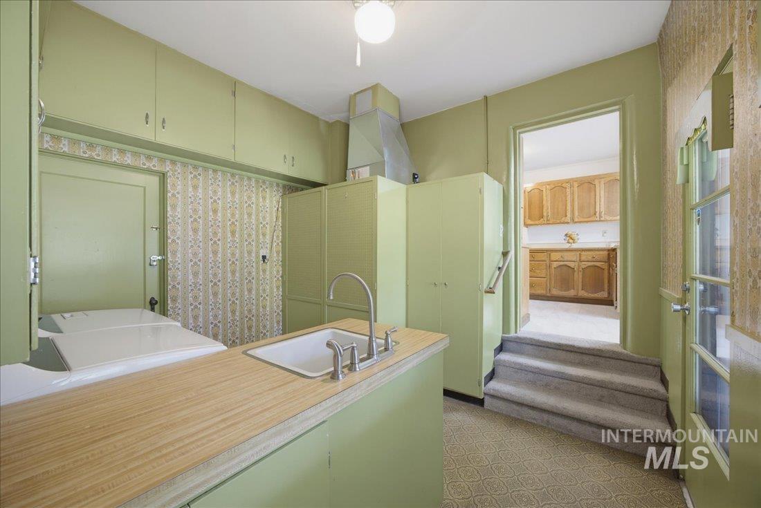 Kitchen area featuring a utility sink with a high-arc faucet, wood-finish countertop, and ample cabinetry