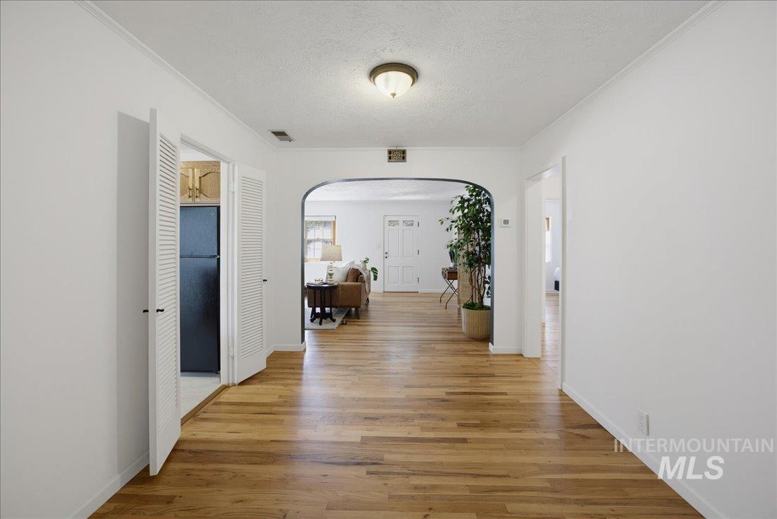 Hardwood-finish flooring throughout, featuring a central arched doorway and louvered bi-fold doors