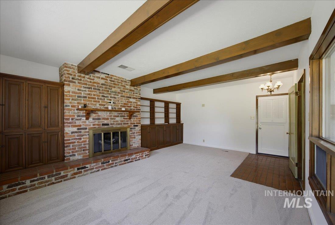 Exposed wood-finish ceiling beams complement a brick fireplace with a raised hearth