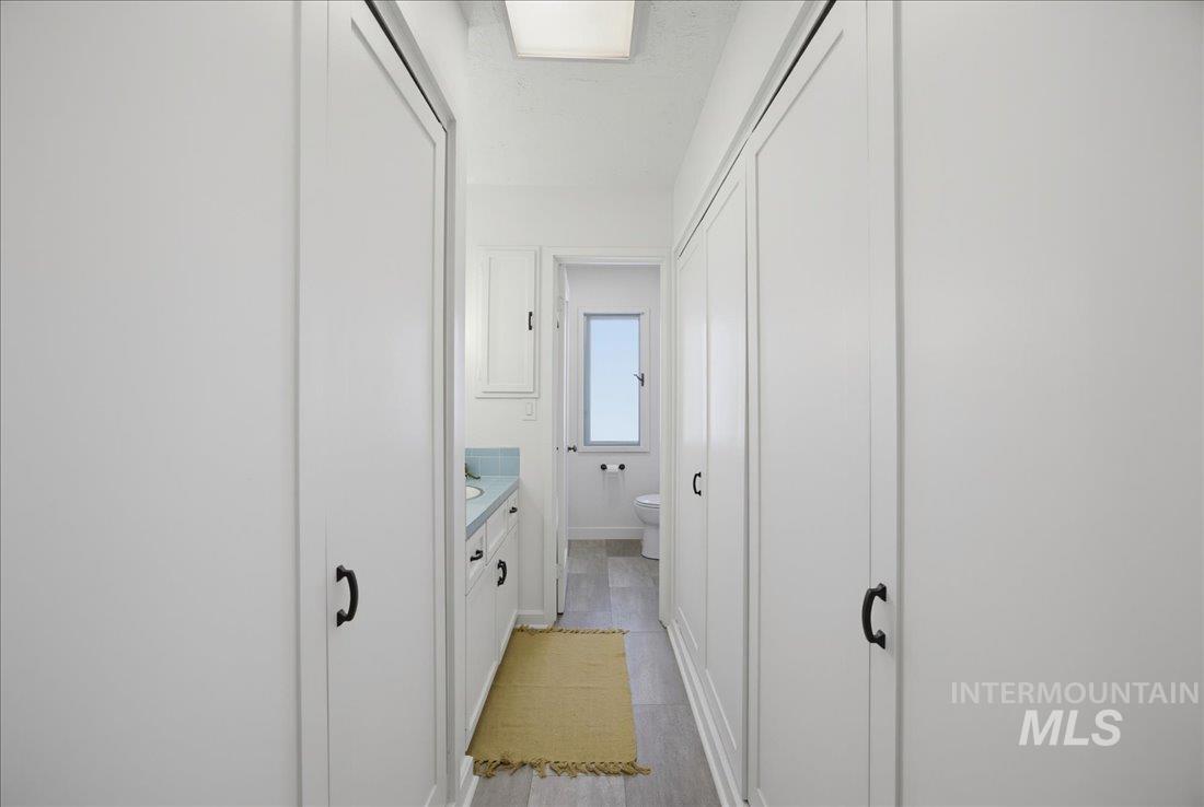 Hallway featuring ample built-in storage with white paneled doors and black hardware