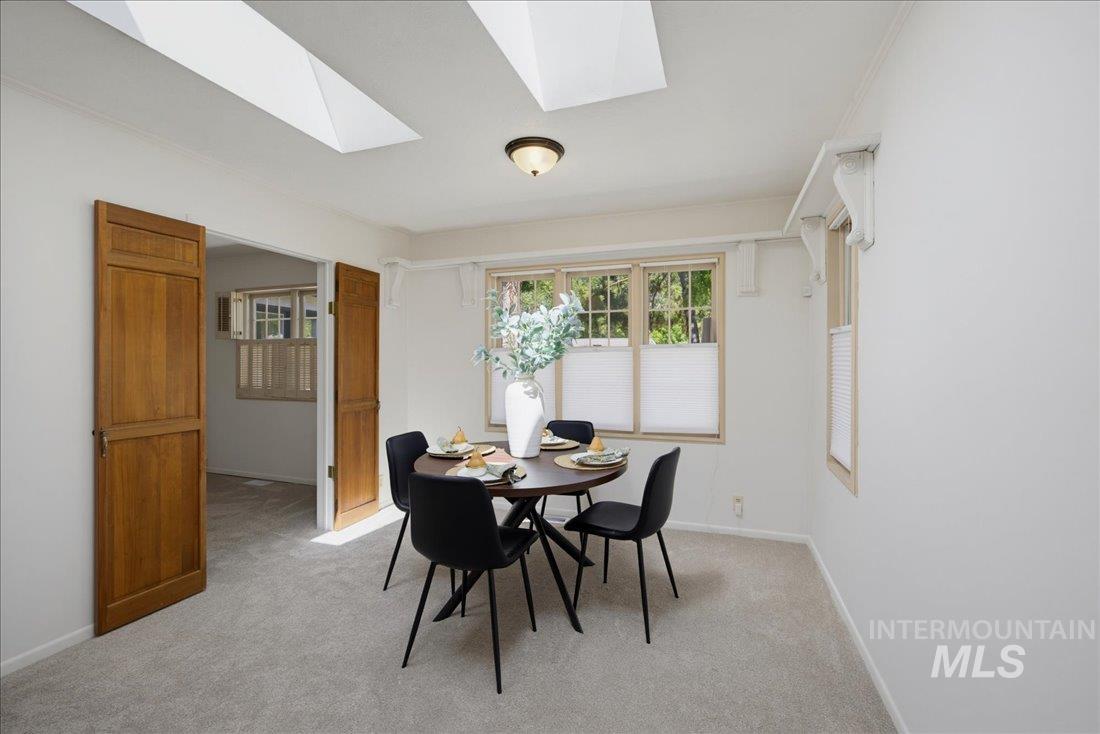 Recessed skylights illuminate this carpeted room featuring a ceiling-mounted light fixture and multiple windows with pleated shades