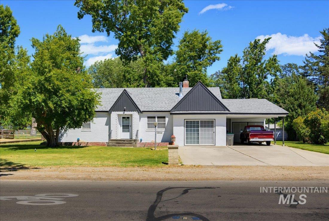 Contemporary ranch-style home featuring white exterior siding, gray shingle roofing, and a black accent gable