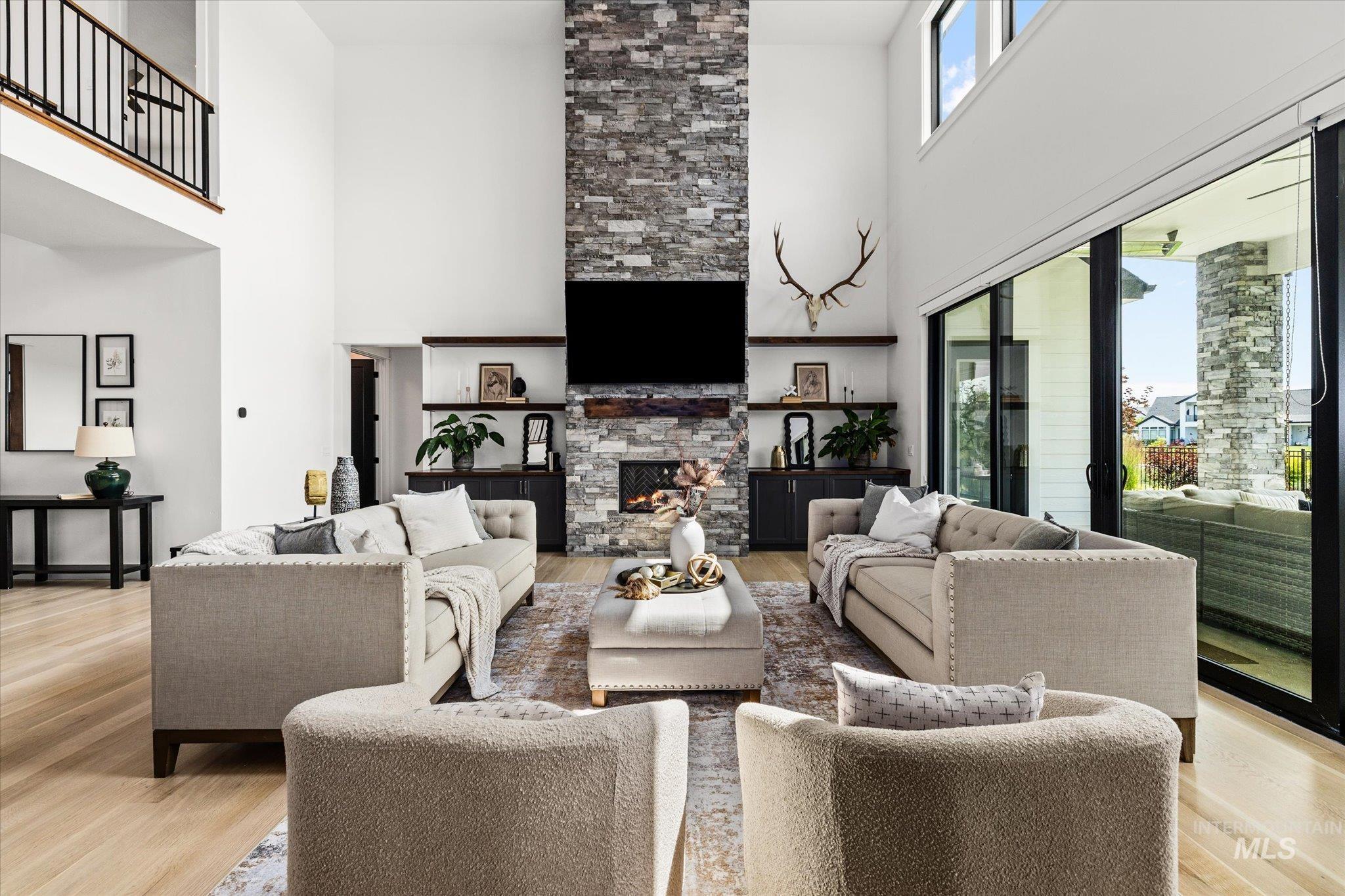 Living room featuring a towering ceiling, light wood finished floors, and a fireplace