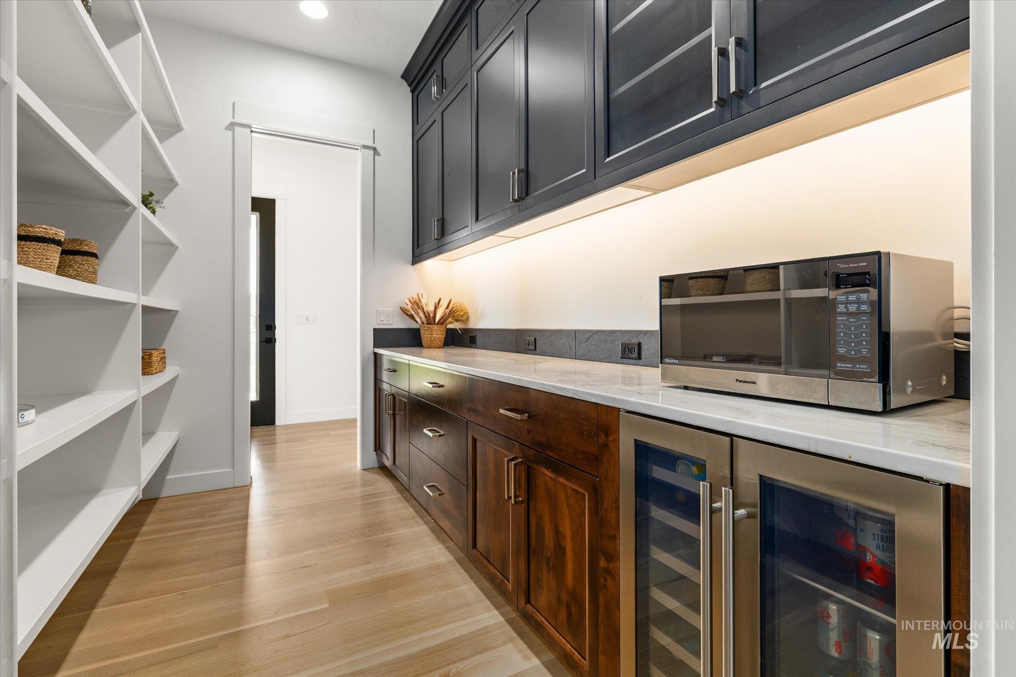 Bar area with beverage cooler, light wood-style flooring, and recessed lighting