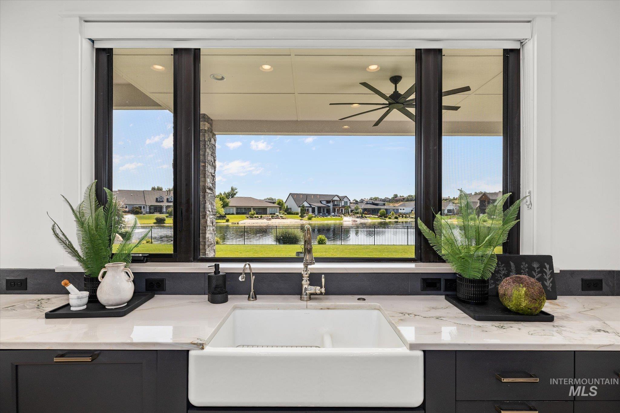 Kitchen with light stone counters, a water view, and gray cabinets