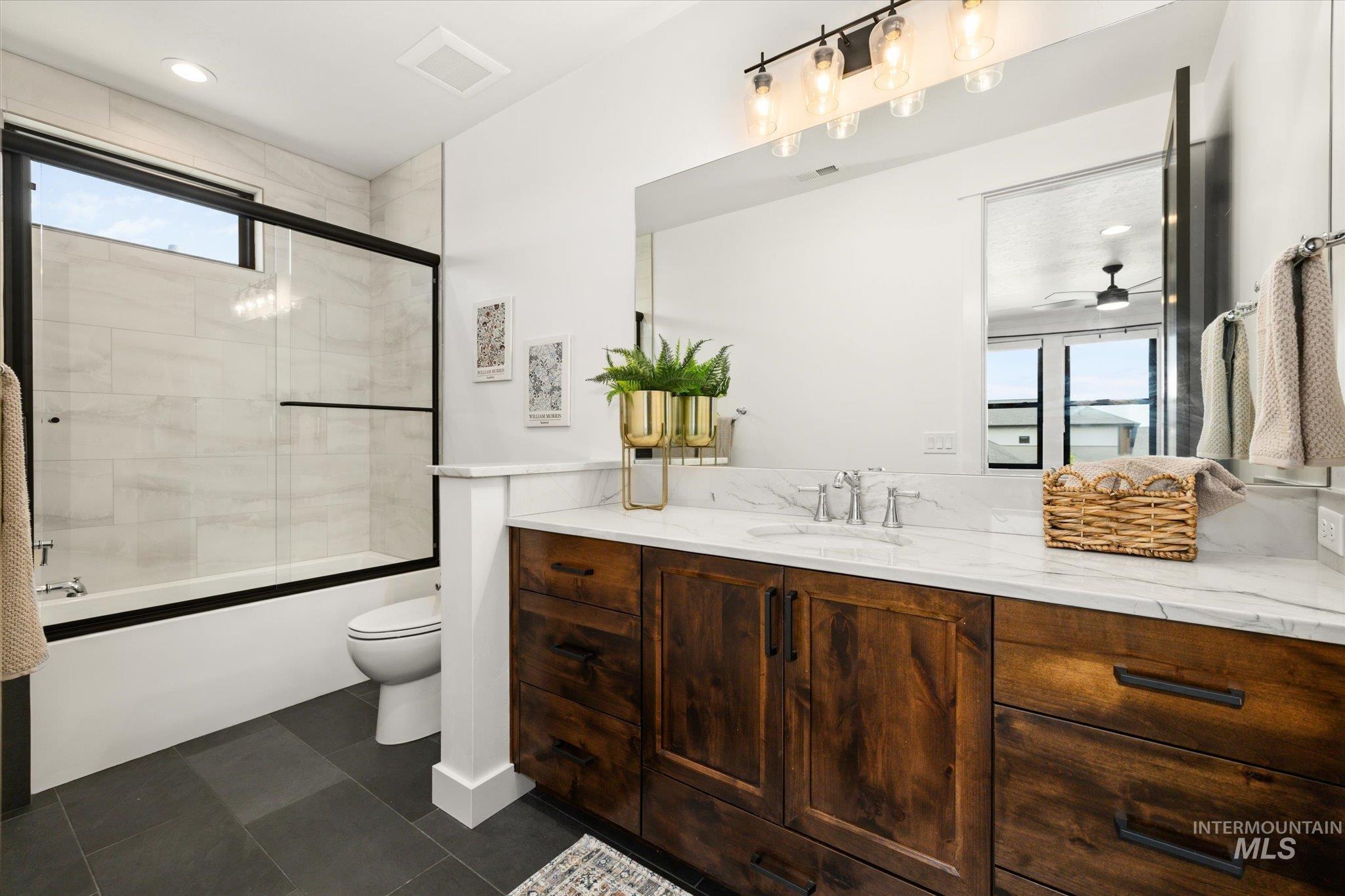 Bathroom featuring vanity, combined bath / shower with glass door, ceiling fan, and tile patterned floors