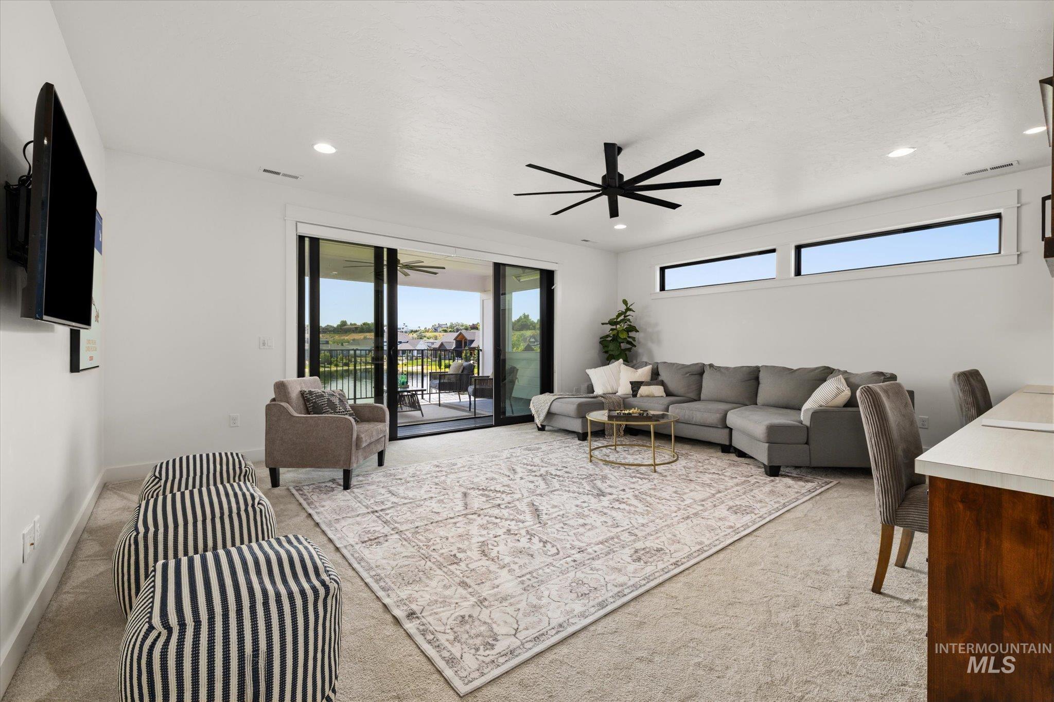 Carpeted living room with ceiling fan and recessed lighting