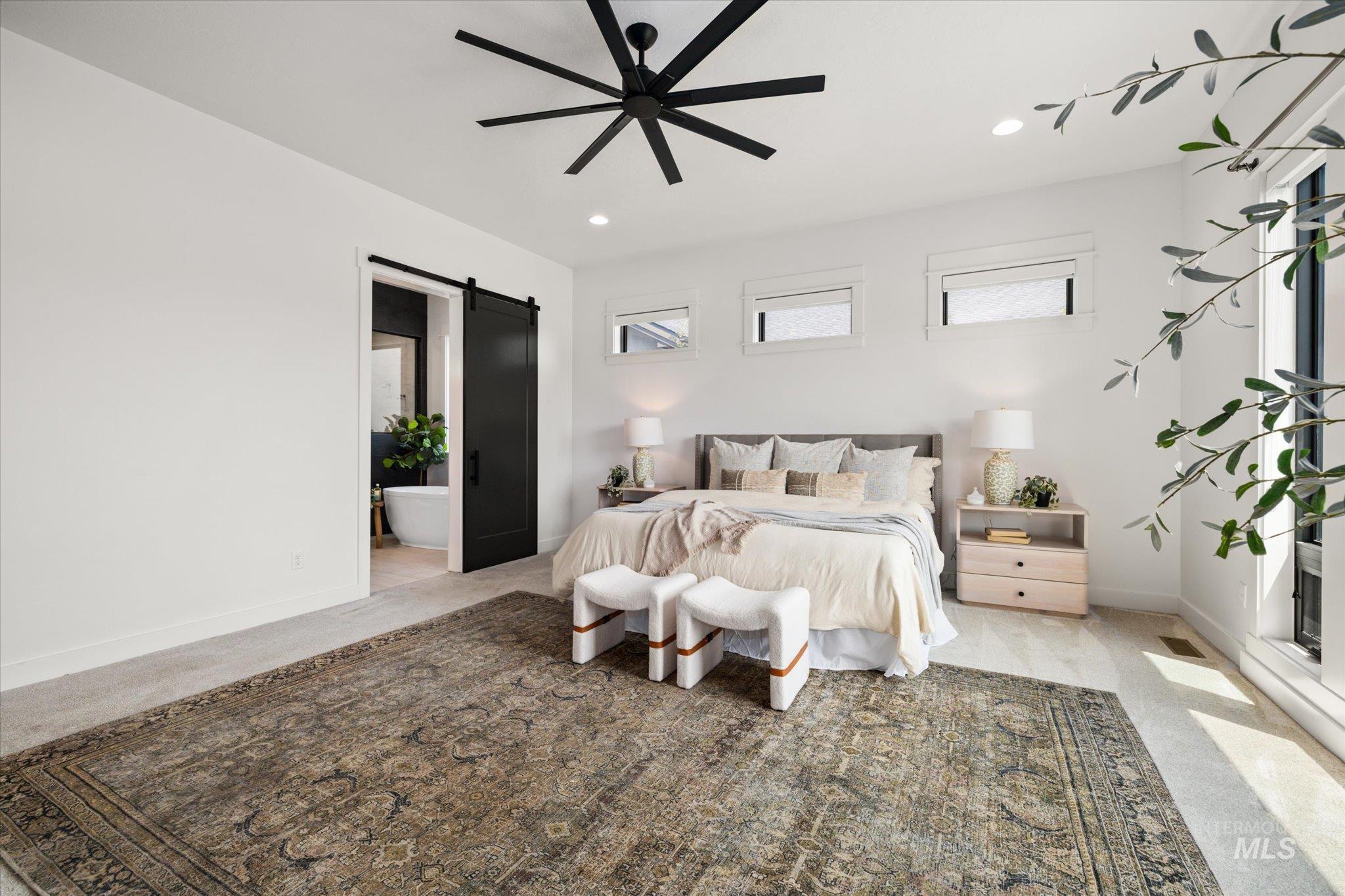 Bedroom with a barn door, light carpet, ensuite bathroom, recessed lighting, and a ceiling fan