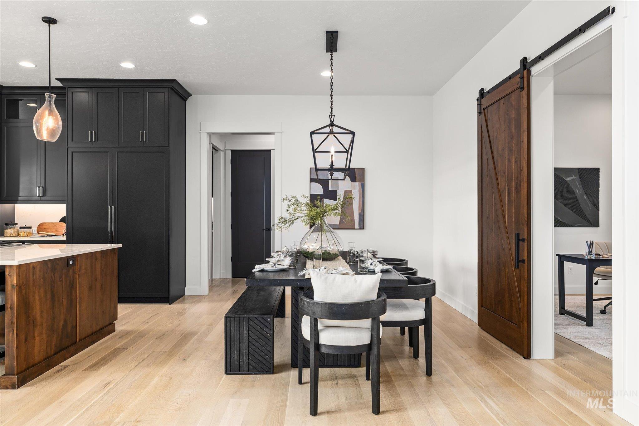 Dining area featuring light wood-style floors, a barn door, and recessed lighting