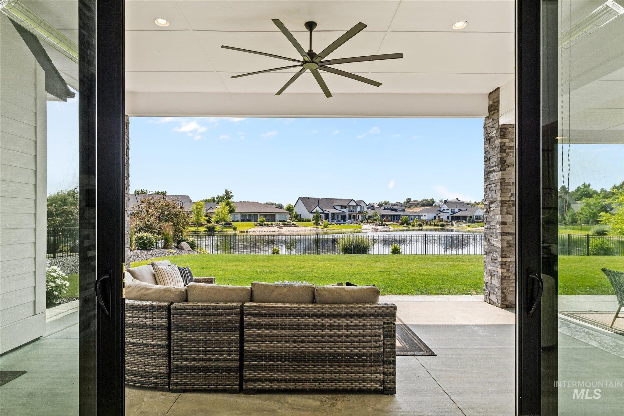 View of patio with a water view, a ceiling fan, an outdoor living space, and a residential view