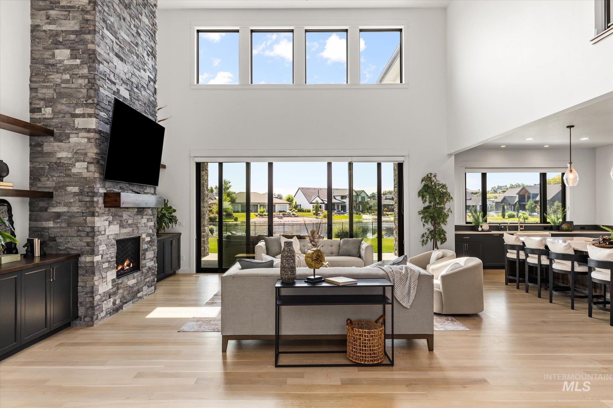 Living area with a fireplace, light wood-style flooring, a towering ceiling, and plenty of natural light